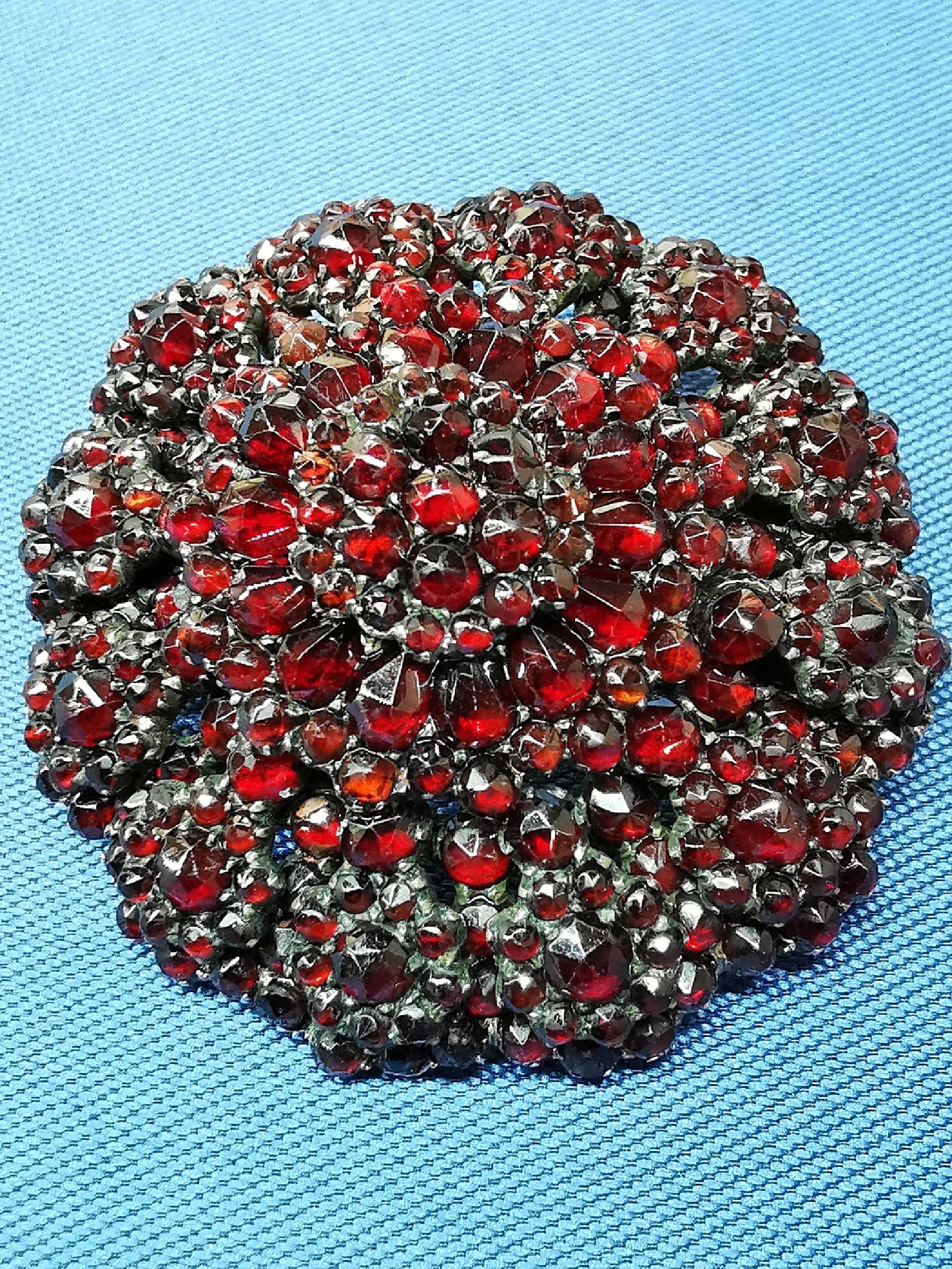 Detail a: Granat-Brosche, um 1880-90, Metall verg., Aufbau in mehreren Ebenen, facett. Granate, D. ca. 4.5 cm, Broschierung sek.