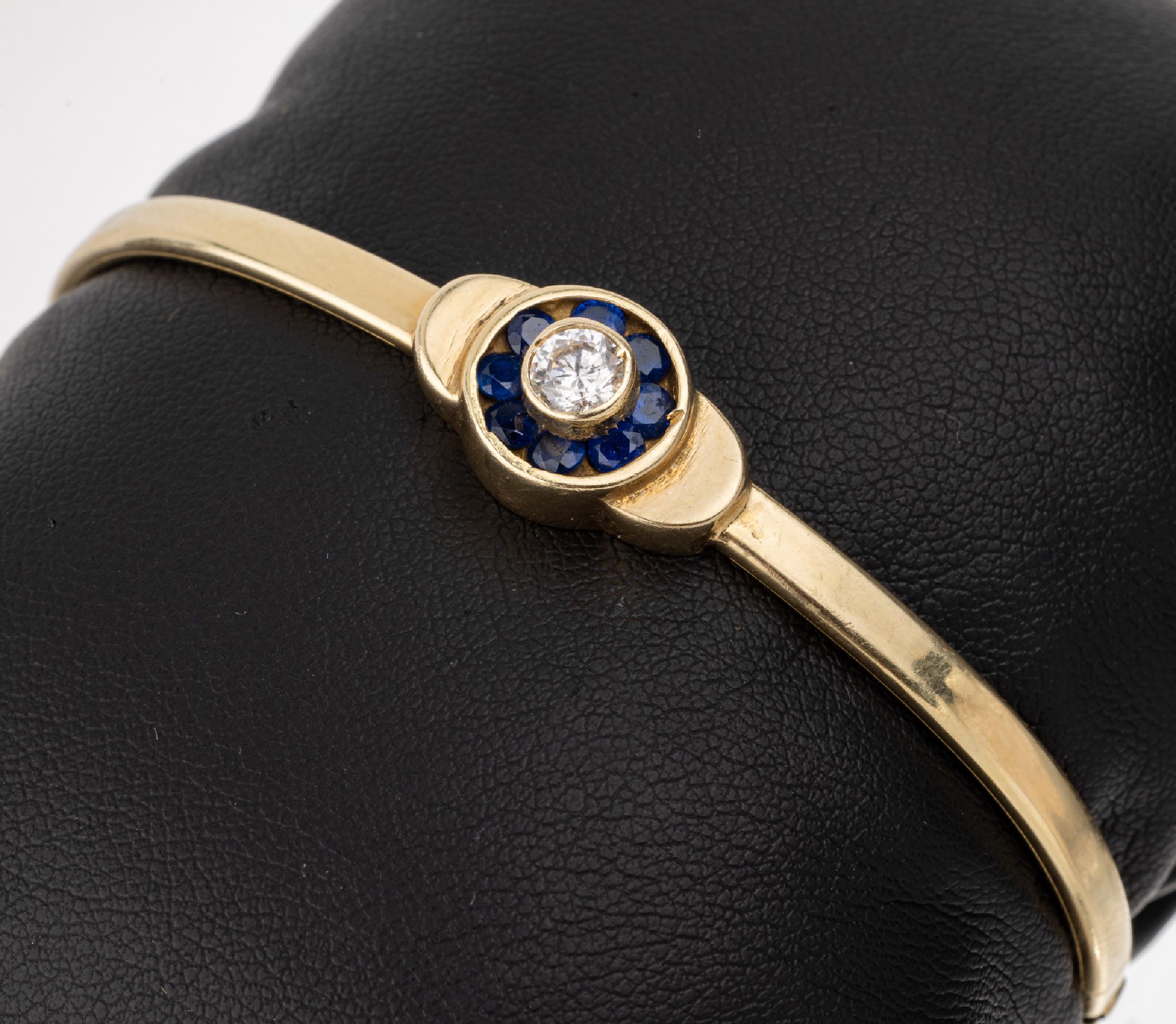 14 kt Gold Armreif, GG 585/000, ca. 6 x 5 cm, Mittelteil mit Diamantimitation (1 Krappe fehlt) umgeben von synth. Saphiren, ca. 8.1 g