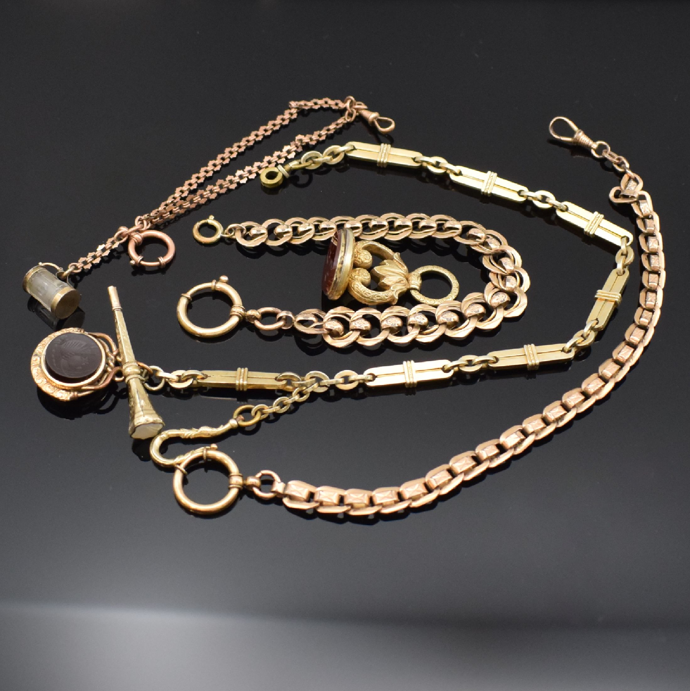 4 vergoldete Taschenuhrketten und ein Petschaft, um 1900, 1) Kette m. Petschaft, Schlüssel, Haken u. verschraubbarem Verschluss, L. ca. 34,5 cm, 2) ...