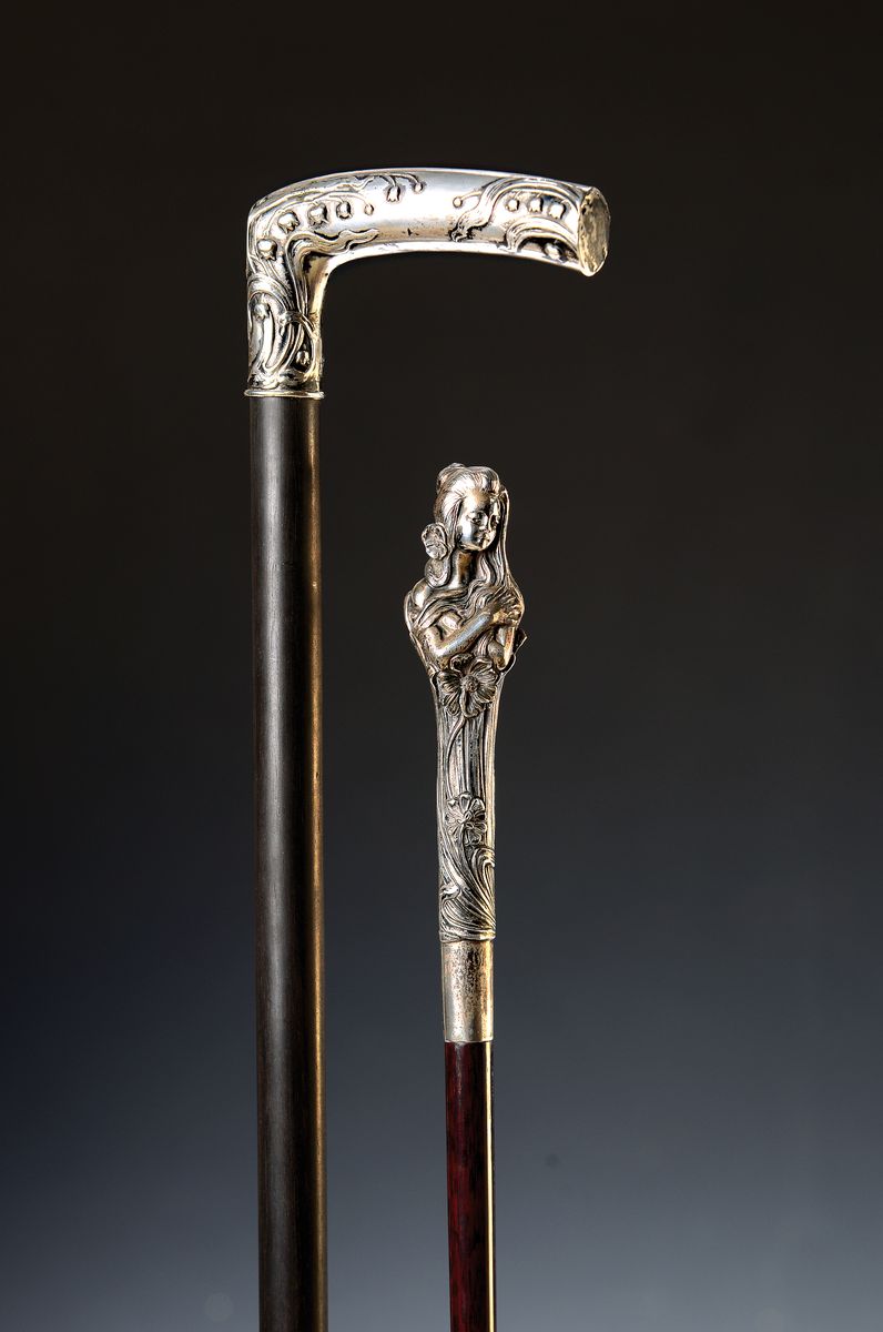 2 Jugendstil-Gehstöcke, deutsch, Griffe 800er-Silber, gemarkt, Holzschuß, Griffe in Forme einer Nymphe bzw. gebogen mit floralem Reliefdekor, L. ...