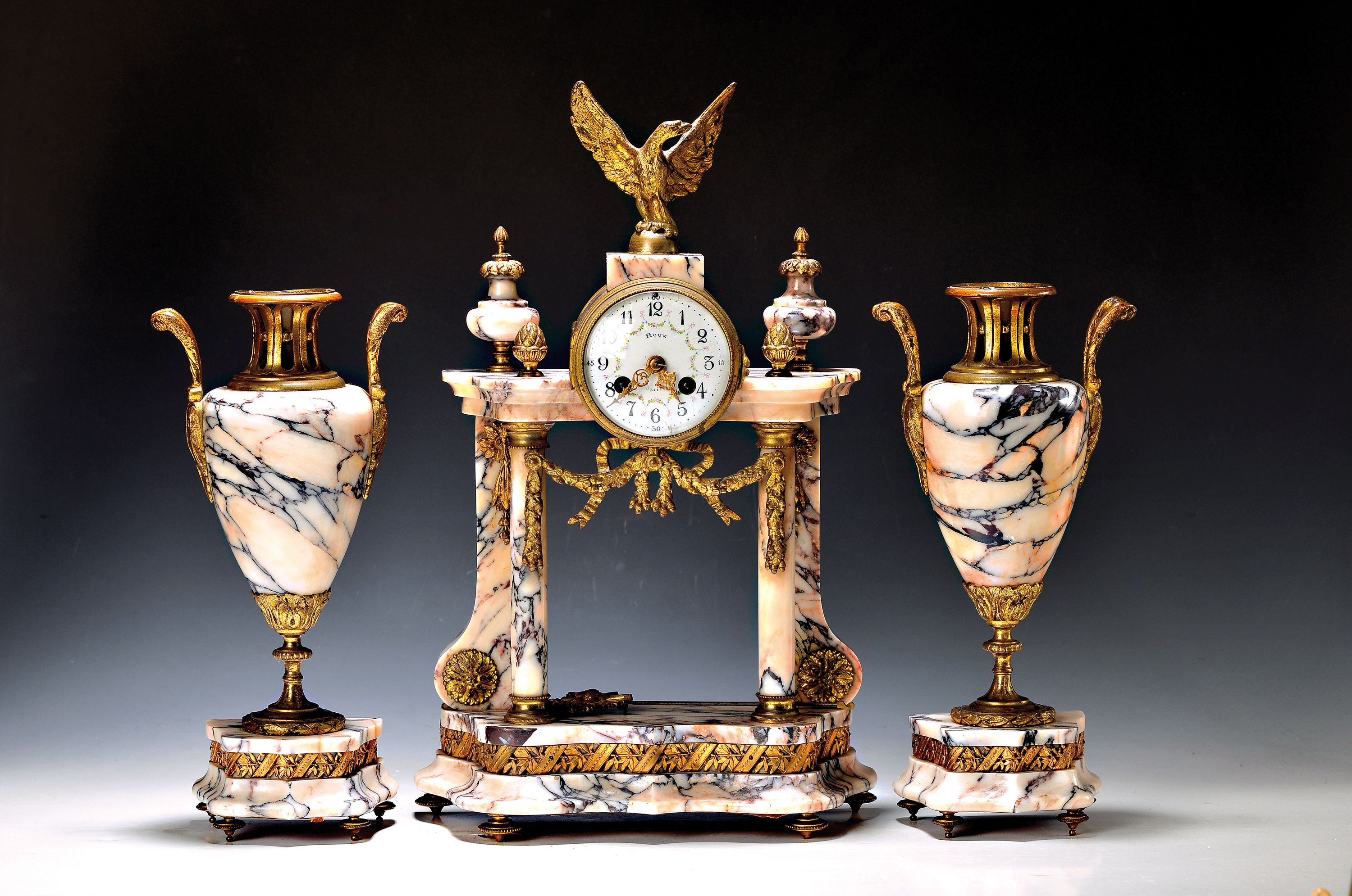 Kaminuhr mit Kerzenbeisteller, Frankreich um 1920/30, geäderter Marmor, Sockel profiliert und geschwungen, Adlerbekrönung, Pinienzapfen, Glasdeckel ...