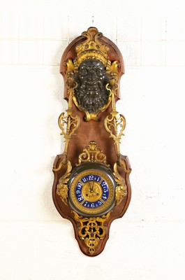 Image 26745608 - Large wall clock with a maskeron, France, around the 19th century, wooden support with avelvet covering (damaged), bearded maskeron crowning the top, looking at the viewer, with a stylized sunray crown, optical holder for the clock, clock built into a profiled metal housing, lion masquerons on the sides, glass lid, four-part blue chapter ring, pendulum movement according to ad. Maugin, Brocot- escapement with steel pallets, rack strike mechanism, strike on bell, pendulum sec., H. approx. 94cm, condition of movement 3, housing2-3