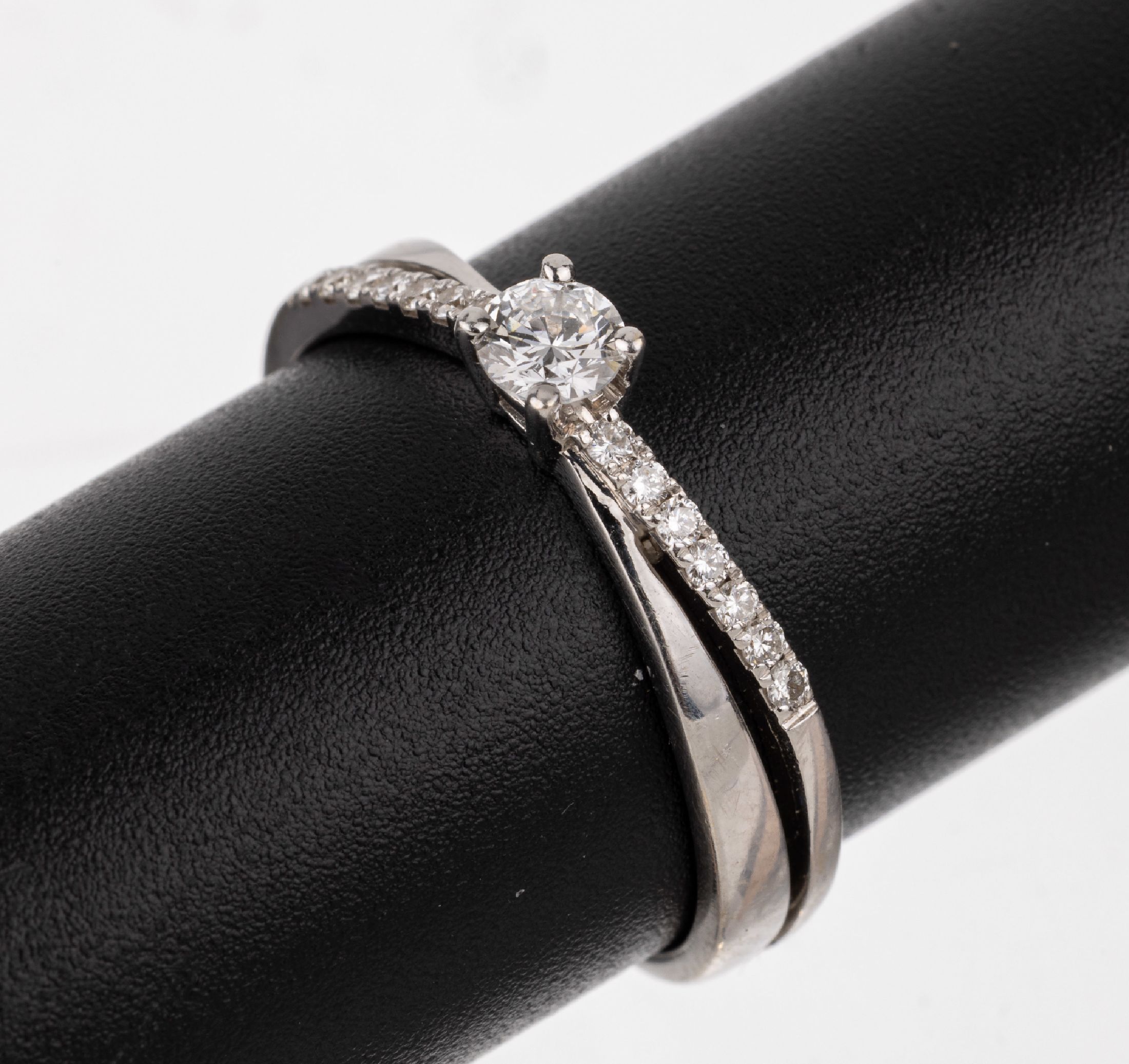 18 kt Gold Brillant-Ring, WG 750/000, mittiger Brillant ca. 0.23 ct Weiß/si, weitere14 Brillanten zus. ca. 0.07 ct Weiß/si, RW 57,ca. 3.3 g