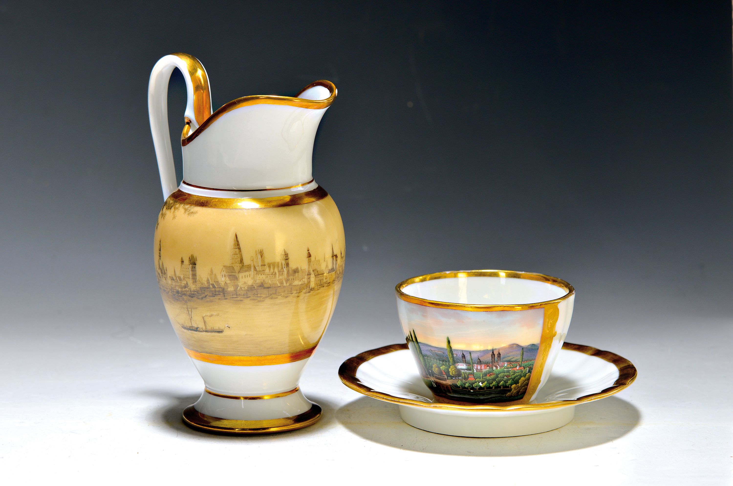 Milchkanne und Tasse mit Untertasse, Biedermeier, um 1820/30, Porzellan, Goldstaffage, H. ca. 18/7 cm, Kanne mit feiner umlaufender Stadtansicht am ...