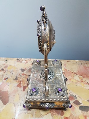 26755226c - Table clock, USA, around 1960/70, based on an antique model, 925 sterling silver housing, inscribed Sander, base all around with pearl strip decoration, profiled, decorated feet, clock is held by large volute struts, glass stones, gold-plated dial, back cover, movement cover decorated, anchor escapement, does not tarnish, with certificate, H. approx. 25cm, condition of work 3-4, housing 3