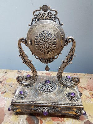 26755226d - Table clock, USA, around 1960/70, based on an antique model, 925 sterling silver housing, inscribed Sander, base all around with pearl strip decoration, profiled, decorated feet, clock is held by large volute struts, glass stones, gold-plated dial, back cover, movement cover decorated, anchor escapement, does not tarnish, with certificate, H. approx. 25cm, condition of work 3-4, housing 3