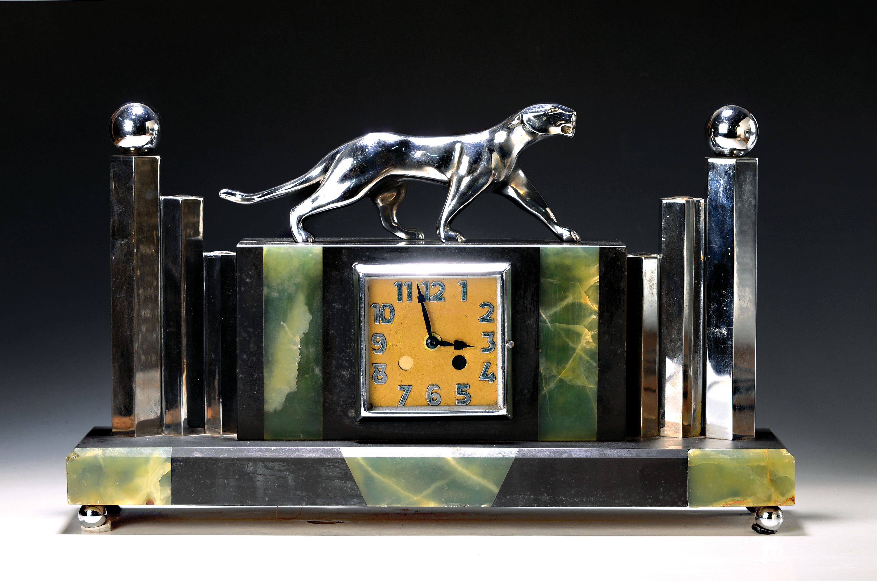 Tischuhr mit Pantherbekrönung, Art Deco, Frankreich um 1930, Schiefergehäuse mit Onyxeinlagen, Tierbekrönung flankiert von abgestuften hexagonalen ...