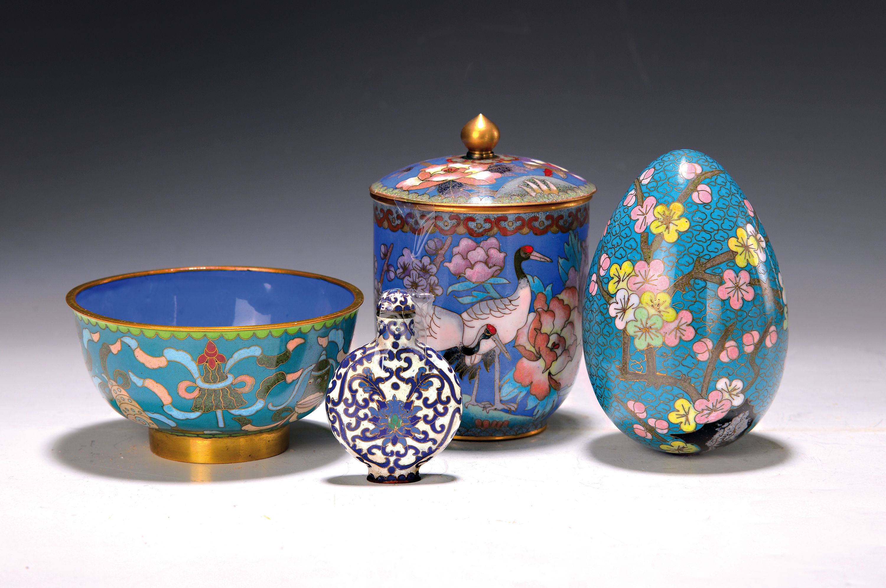 Vier Teile Cloisonne, China, Mitte bis 2. Hälfte 20. Jh., Deckeldose mit Kranichdekor, H. ca. 12.5cm, Schale mit Glückssymbolen, D. 11.5cm, Ei mit ...