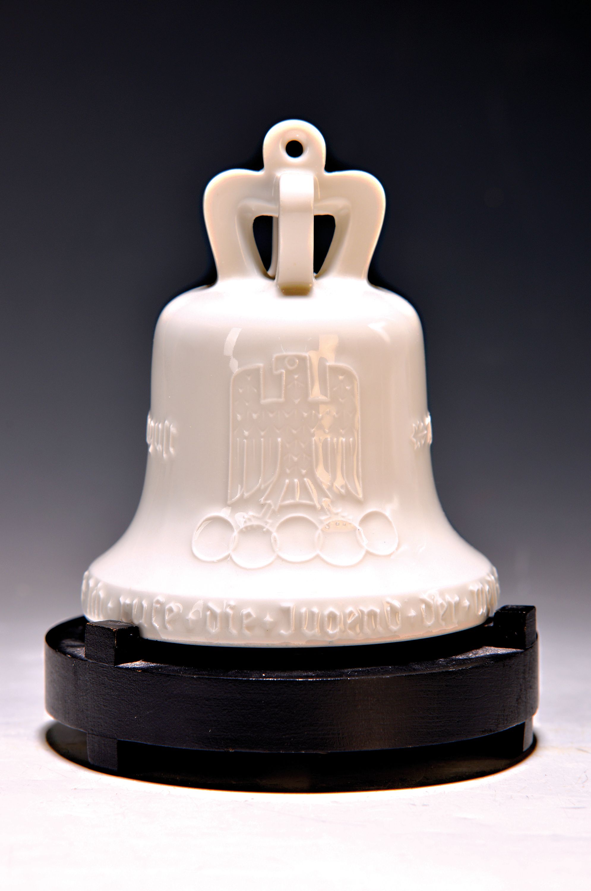 Olympiaglocke der Olympiade 1936, KPM Berlin, Weißporzellan, mit Klöppel, schwarzer Aufsteller, Szeptermarke innen, Aufhänger min. best., H. 13 cm