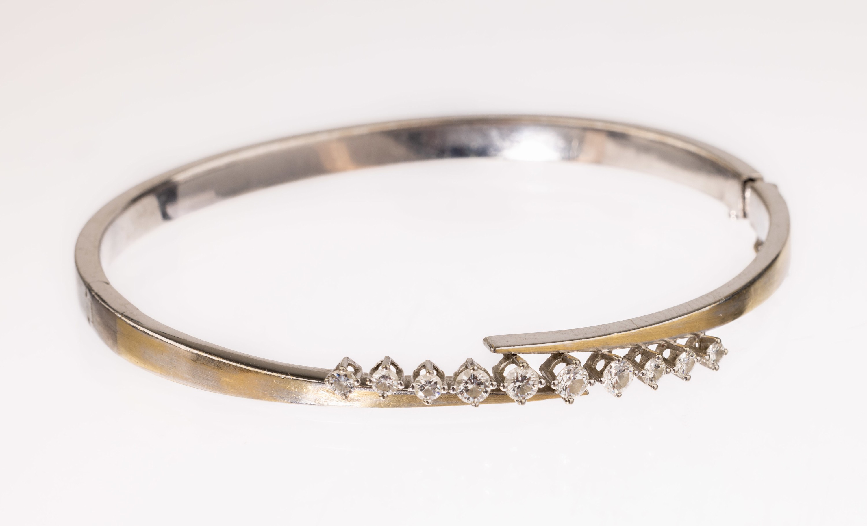 18 kt Gold Brillant-Armreif, WG 750/000, 10Brillanten zus. ca. 0.64 ct Weiß/si, ca. 6 cm,Kastenschloss mit Sicherheitsacht, ca. 16.2 g