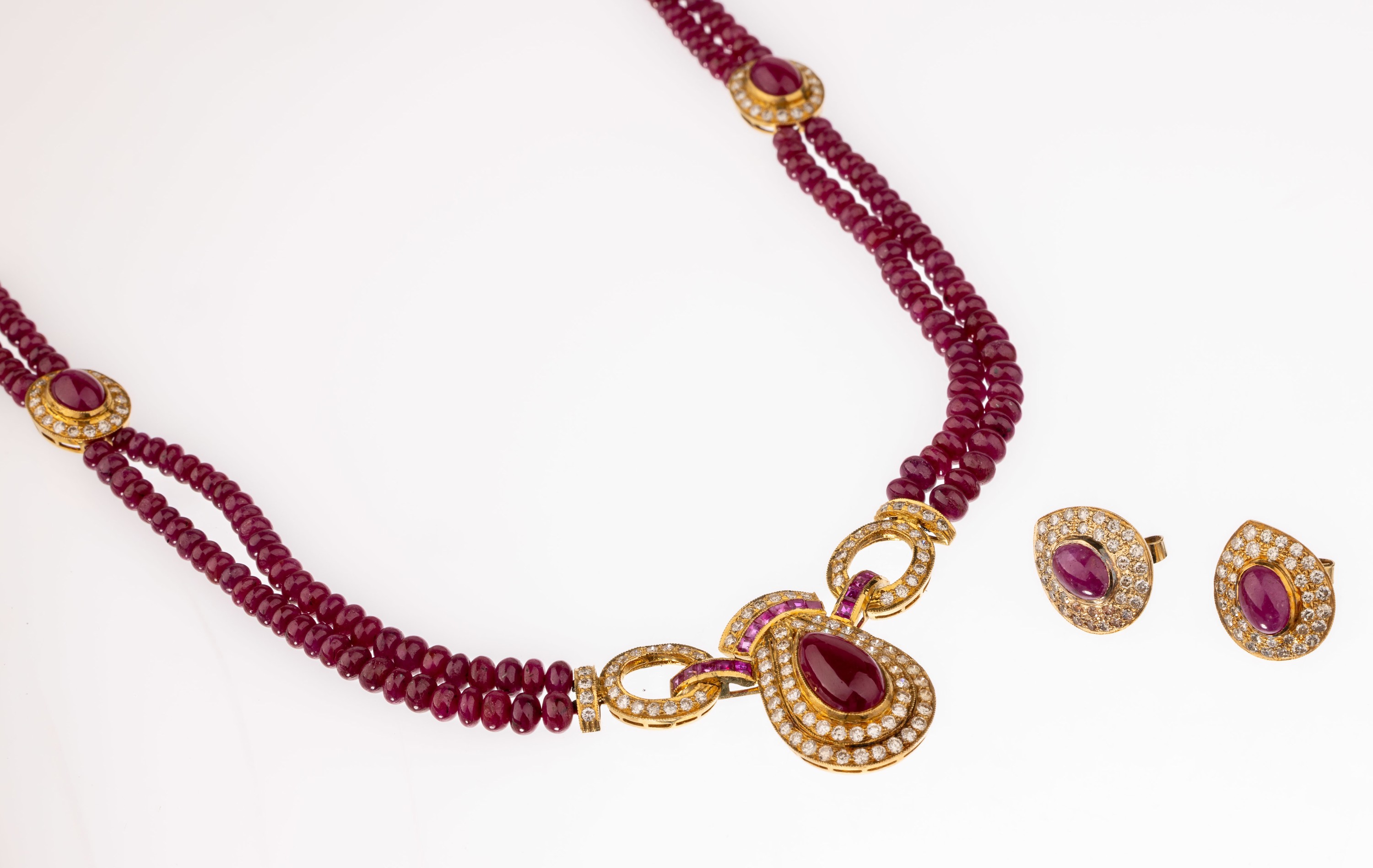 18 kt Gold Rubin-Brillant-Schmuckset, GG 750/000, best. aus: Collier und Paar Ohrstecker, bes. mit 5 ovale und 1 tropfenf. Rubincabochon zus. ca. ...