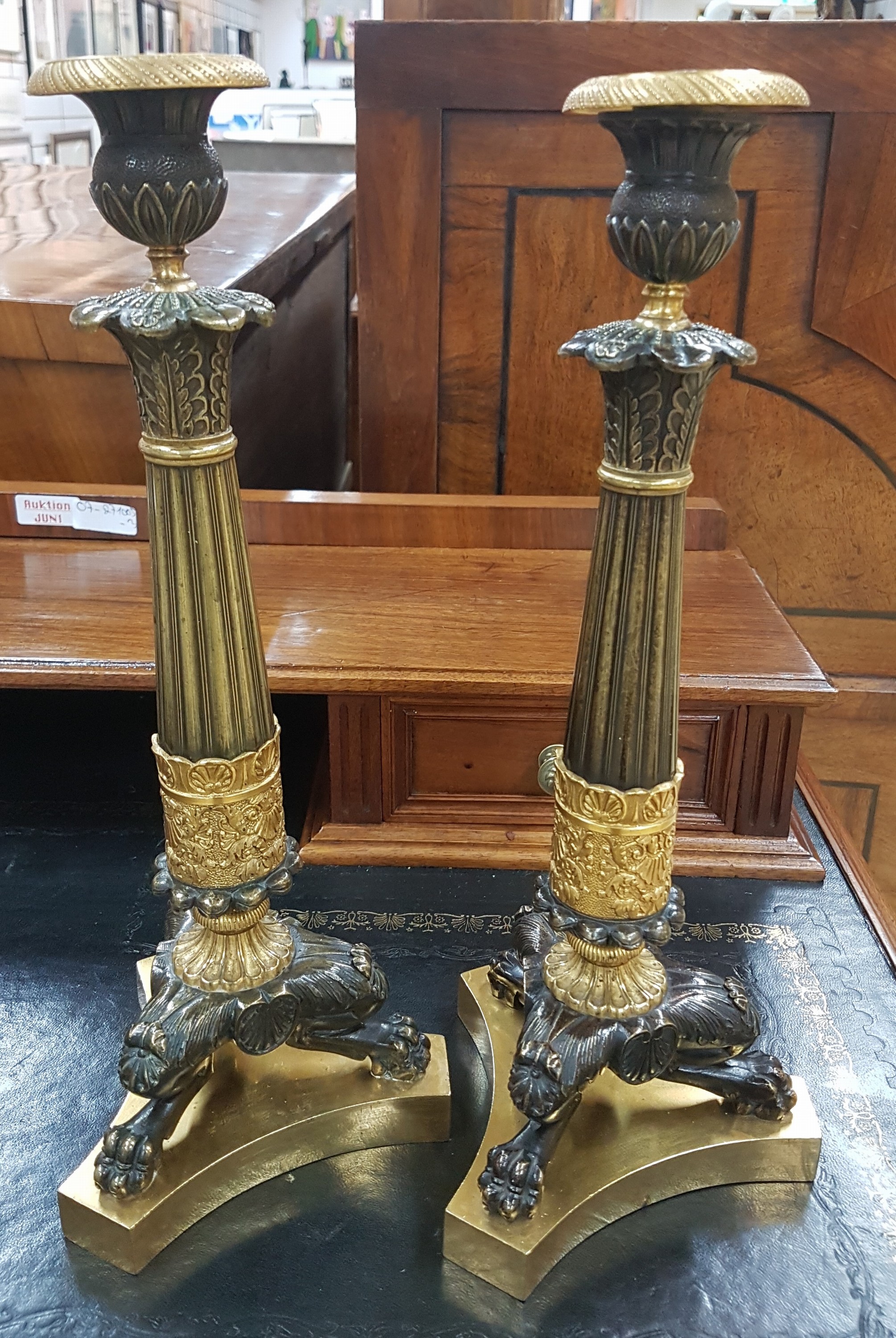 Detail a: Paar Kerzenleuchter, Frankreich, um 1820-30, reich reliefierter Bronzeguß z.T. vergoldet, auf drei Klauenfüßen stehend, kannelierte Säulen mit ...