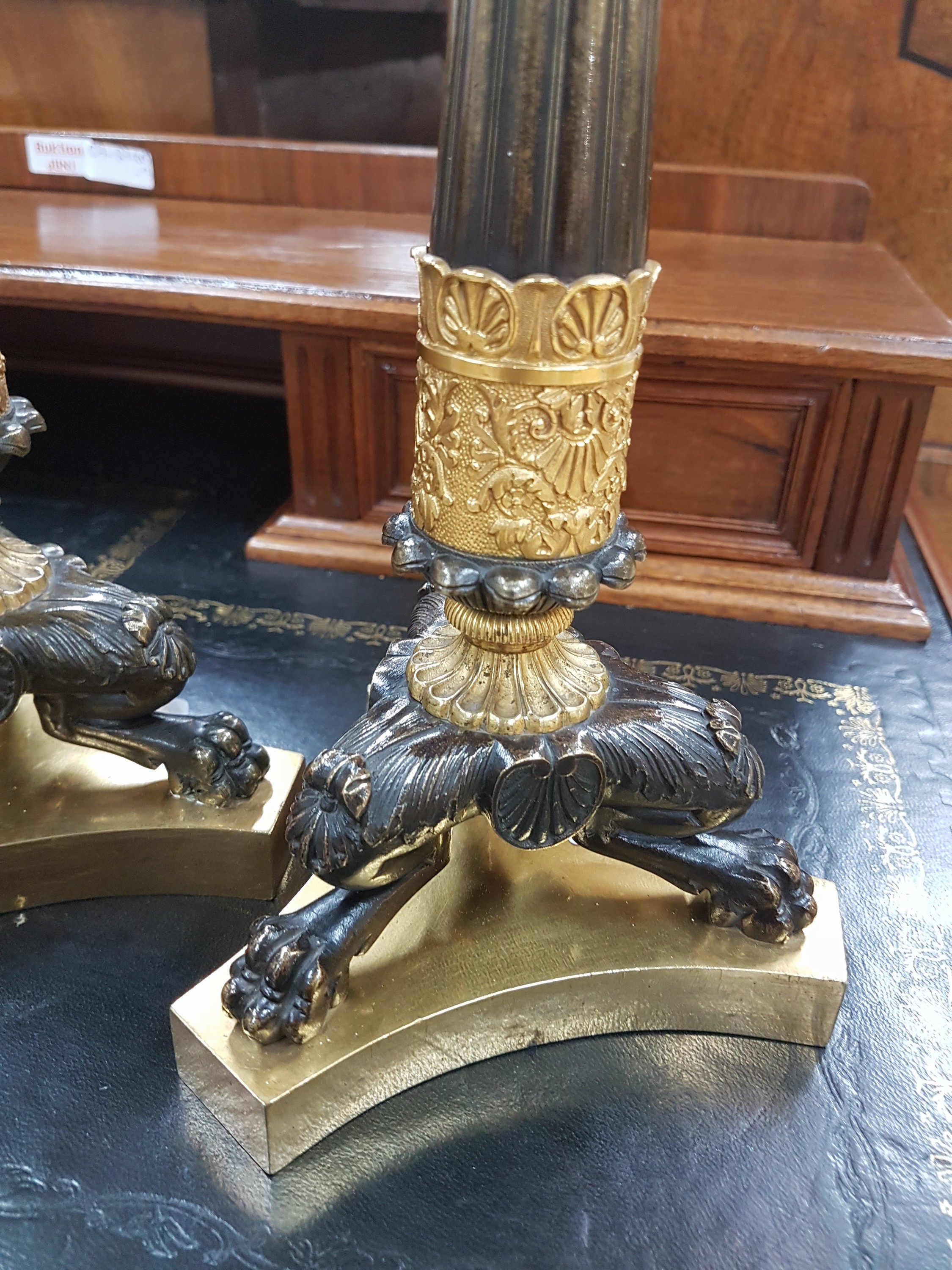 Detail b: Paar Kerzenleuchter, Frankreich, um 1820-30, reich reliefierter Bronzeguß z.T. vergoldet, auf drei Klauenfüßen stehend, kannelierte Säulen mit ...