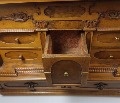 26769341g - Model cabinet cupboard, South German, 18th century, oak veneer, lid with drawer, behind it a lock for the lid drawer, old lock and fittings, former 2-door front is missing, 6 drawers, Renaissance decor, drawers mainly lined with marble paper, restored, 4 secondary feet, 29x36x26 cm, 1 key available