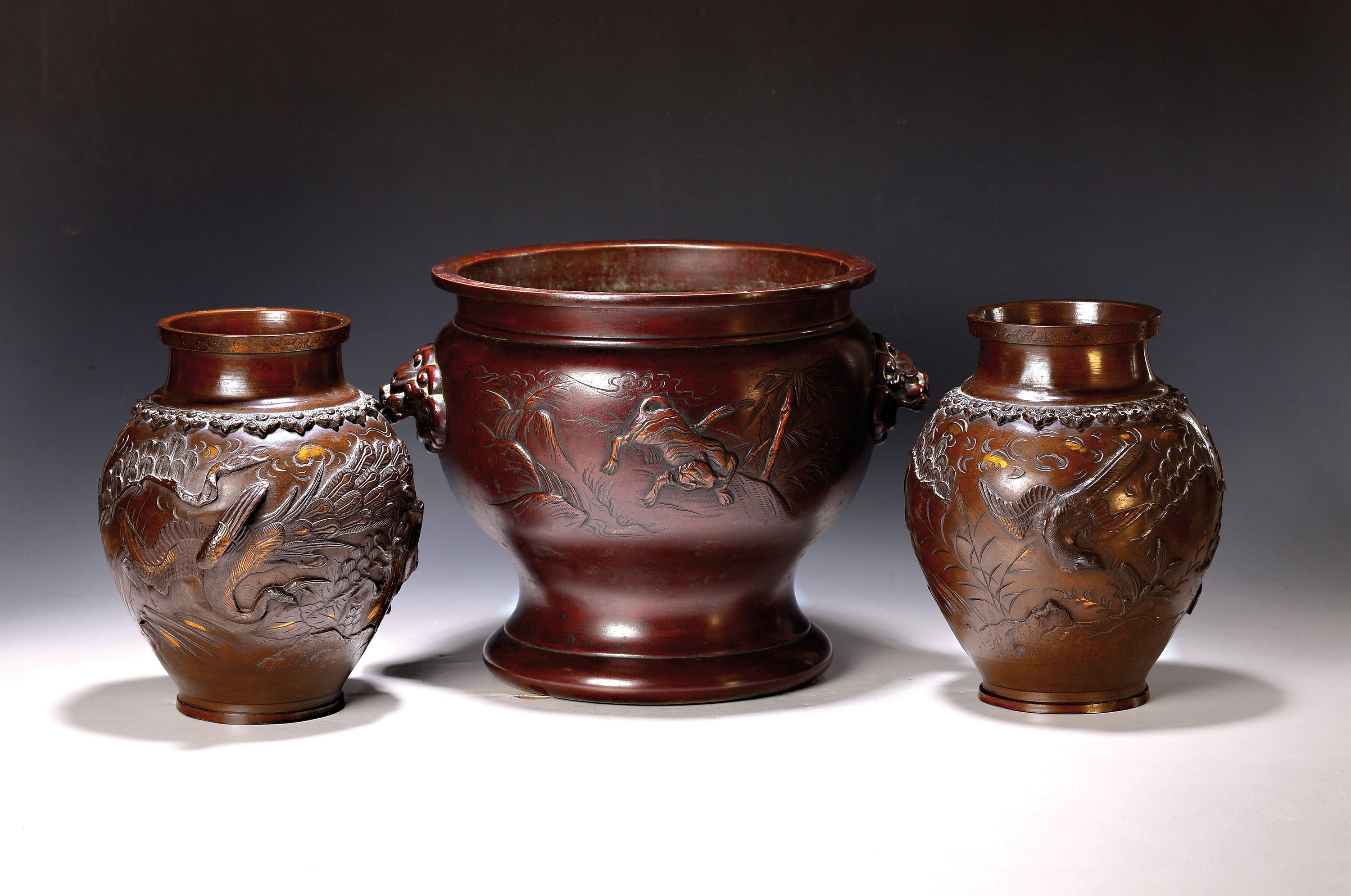 Drei Bronzevasen, Japan, um 1900, Bronze braun patiniert, partiell vergoldet, Reliefdekor mit floralen und mythologischen Motiven, Vasenpaar und ...