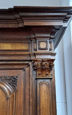 26770581b - Baroque cupboard/pilaster cupboard, probably Brunswick, around 1720, walnut veneer on oak body, carvings and profiles in solid oak, front with 3 pilasters and Corinthian capitals, cornice and base double cranked, doors and sides with cushion fillings, base with 2 drawers, orig. Locks, door with orig. Locomotive, original key and original Brass fittings, approx. 228 x 208 x 78 cm, condition 2