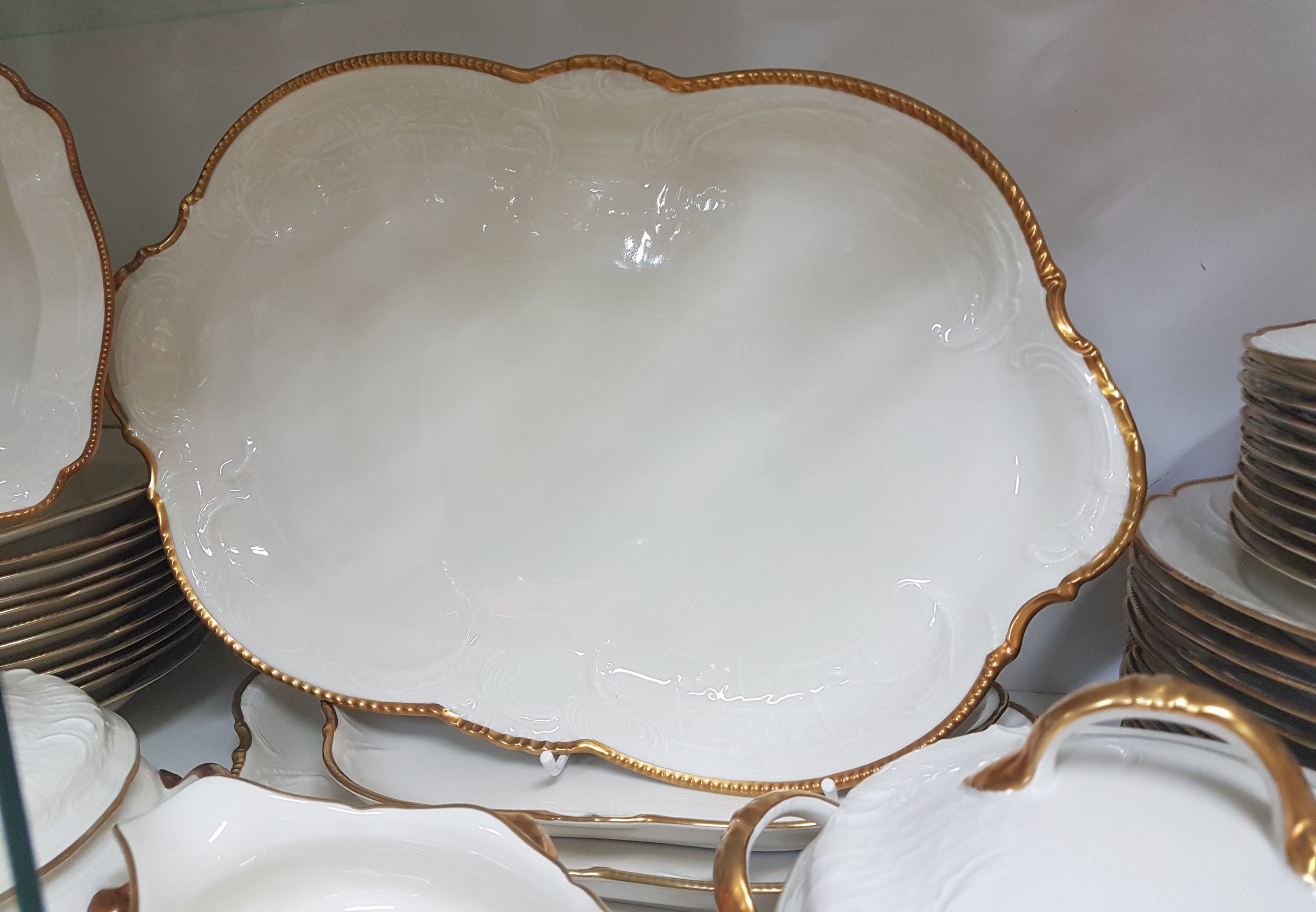 Detail b: Speiseservice, Rosenthal, Sanssouci, 20.Jh., Porzellan, Goldrand, Fahne mit Muschelwerk im Relief, 12 Speiseteller D. 25cm, 12 Suppenteller D. 24cm, ...