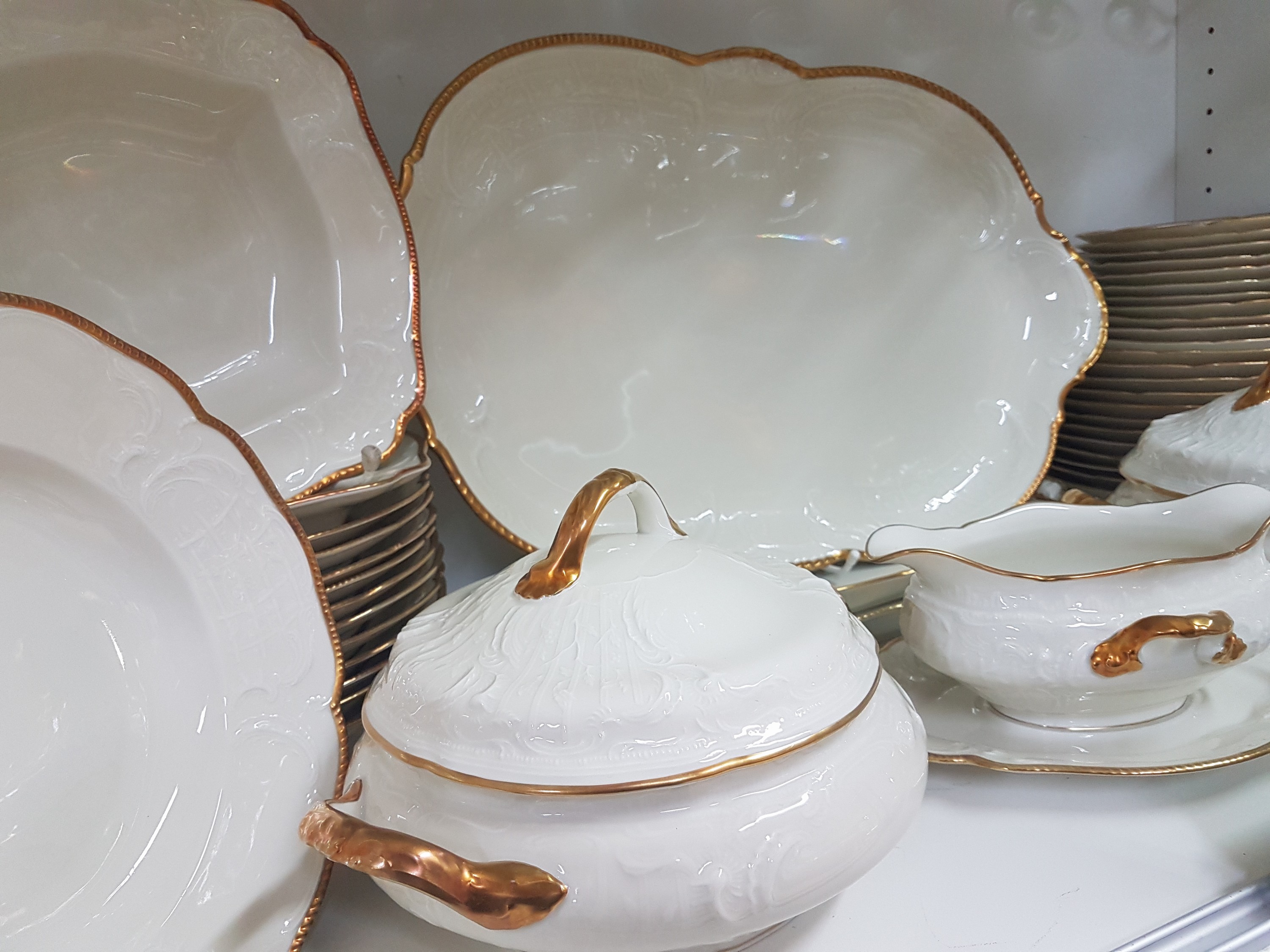 Detail d: Speiseservice, Rosenthal, Sanssouci, 20.Jh., Porzellan, Goldrand, Fahne mit Muschelwerk im Relief, 12 Speiseteller D. 25cm, 12 Suppenteller D. 24cm, ...