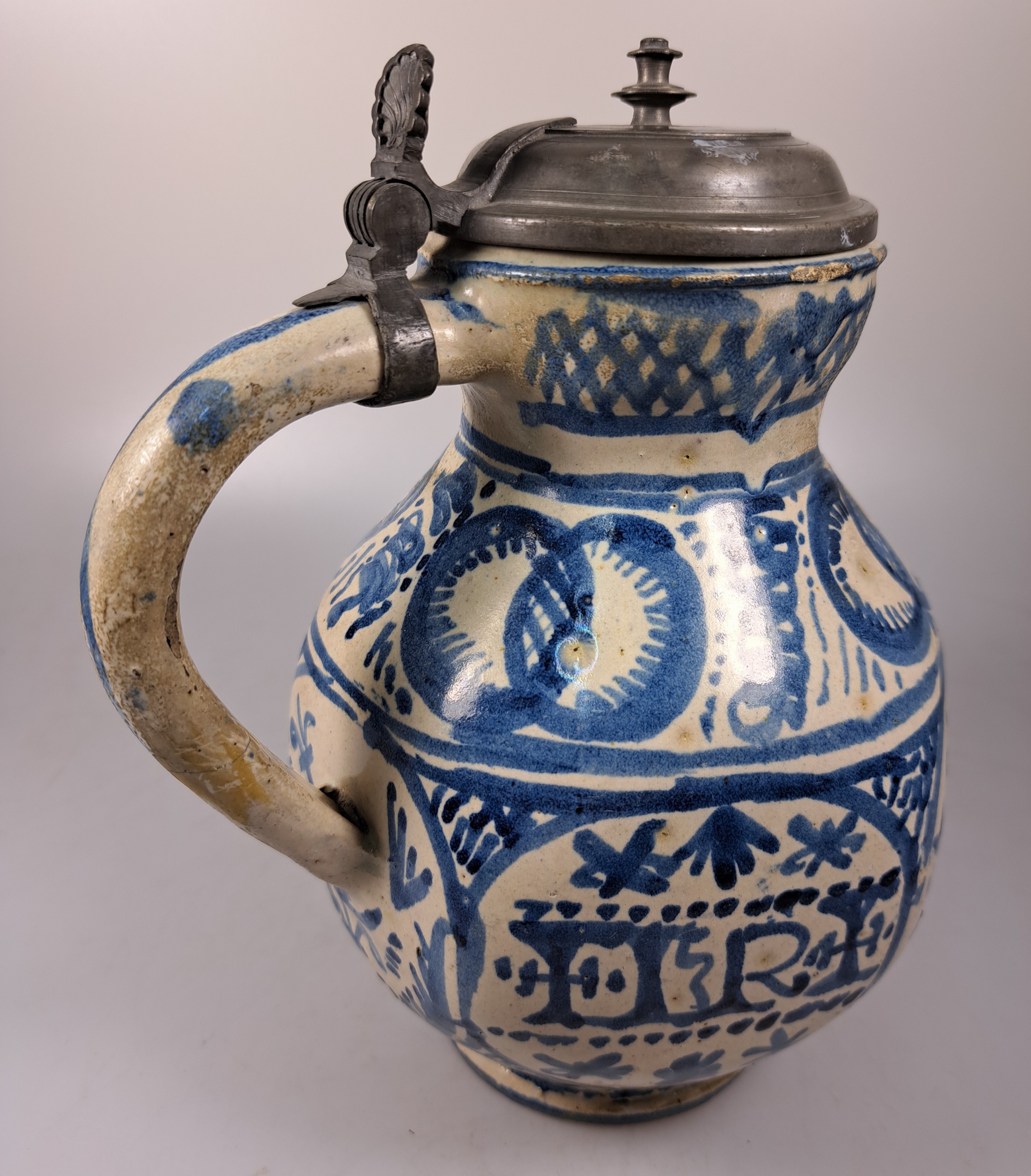 Detail f: Sechskantkrug, Dießen/Ammersee, 17. Jh., Fayence, sechsfach gedrückter Bauch, blaue Scharffeuerfarben, religiöse Motive und Granatäpfel, die ...