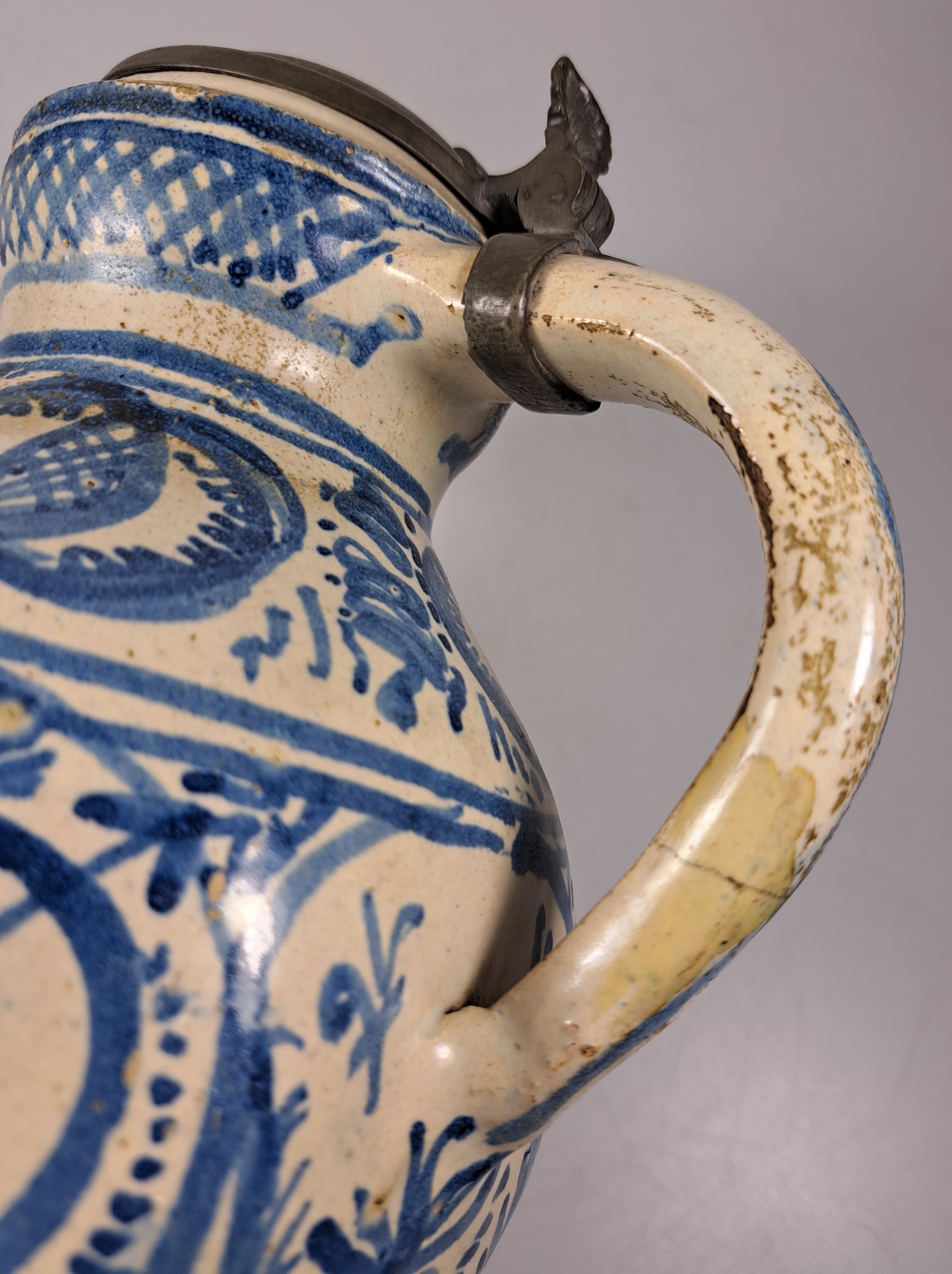 Detail i: Sechskantkrug, Dießen/Ammersee, 17. Jh., Fayence, sechsfach gedrückter Bauch, blaue Scharffeuerfarben, religiöse Motive und Granatäpfel, die ...
