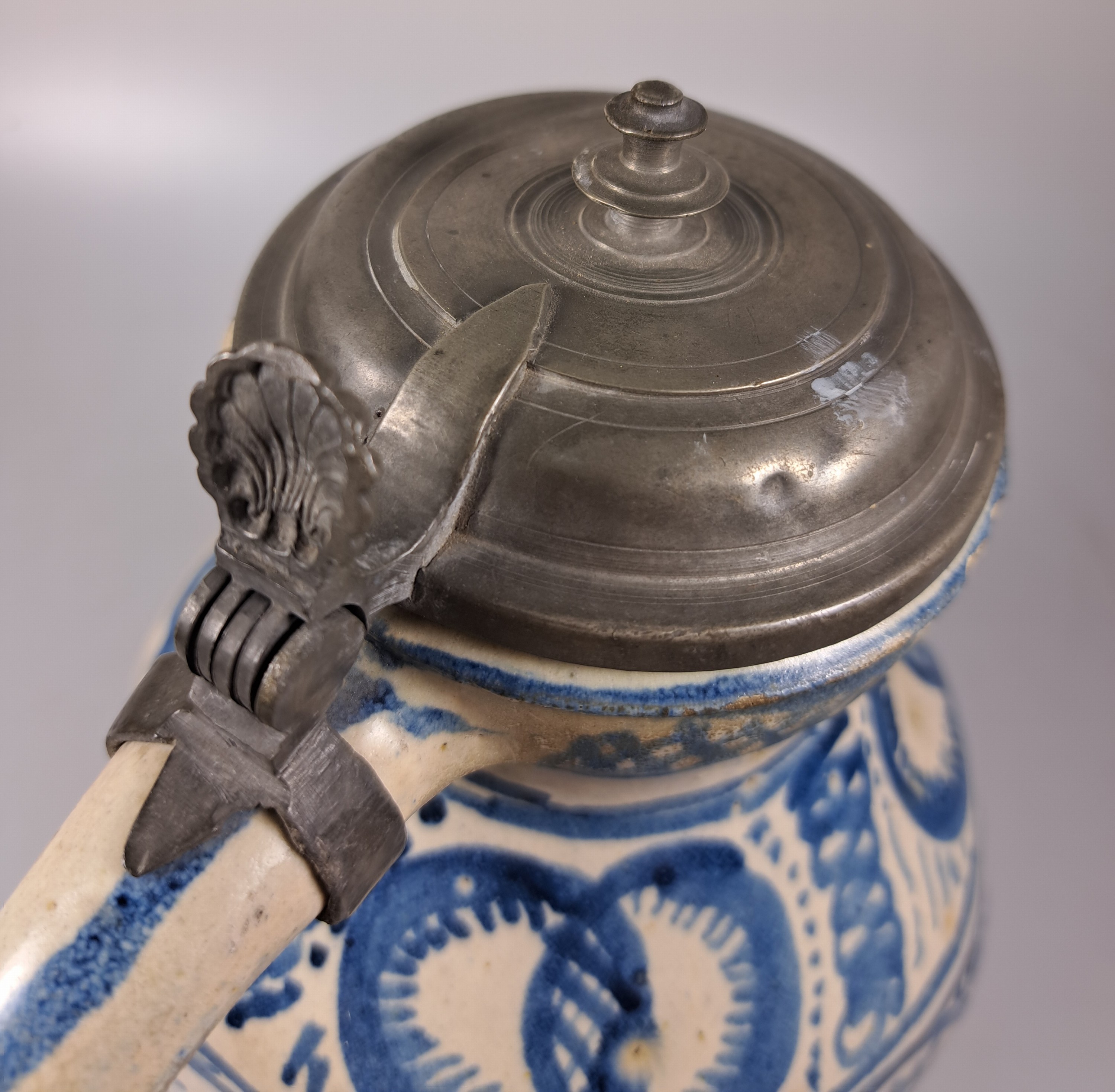 Detail j: Sechskantkrug, Dießen/Ammersee, 17. Jh., Fayence, sechsfach gedrückter Bauch, blaue Scharffeuerfarben, religiöse Motive und Granatäpfel, die ...