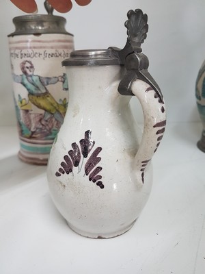 26778677l - Seven jugs, German, 18th century, mostly faience, roller jugs with tin lids, painted, one jug slightly Chipped, a jug with a crack, two pear jugs, decor nobleman with bottle, height approx. 15.5 cm, jug with tin lid and toast, height 16 cm, small pear shaped jug with pewter lid, height 16 cm, pear shaped jug with bouquet of flowers, height 22 cm, l. best.; Stoneware jug , vegetal incised decoration, pewter lid, height 29 cm, all parts with slight Age damage or signs of age