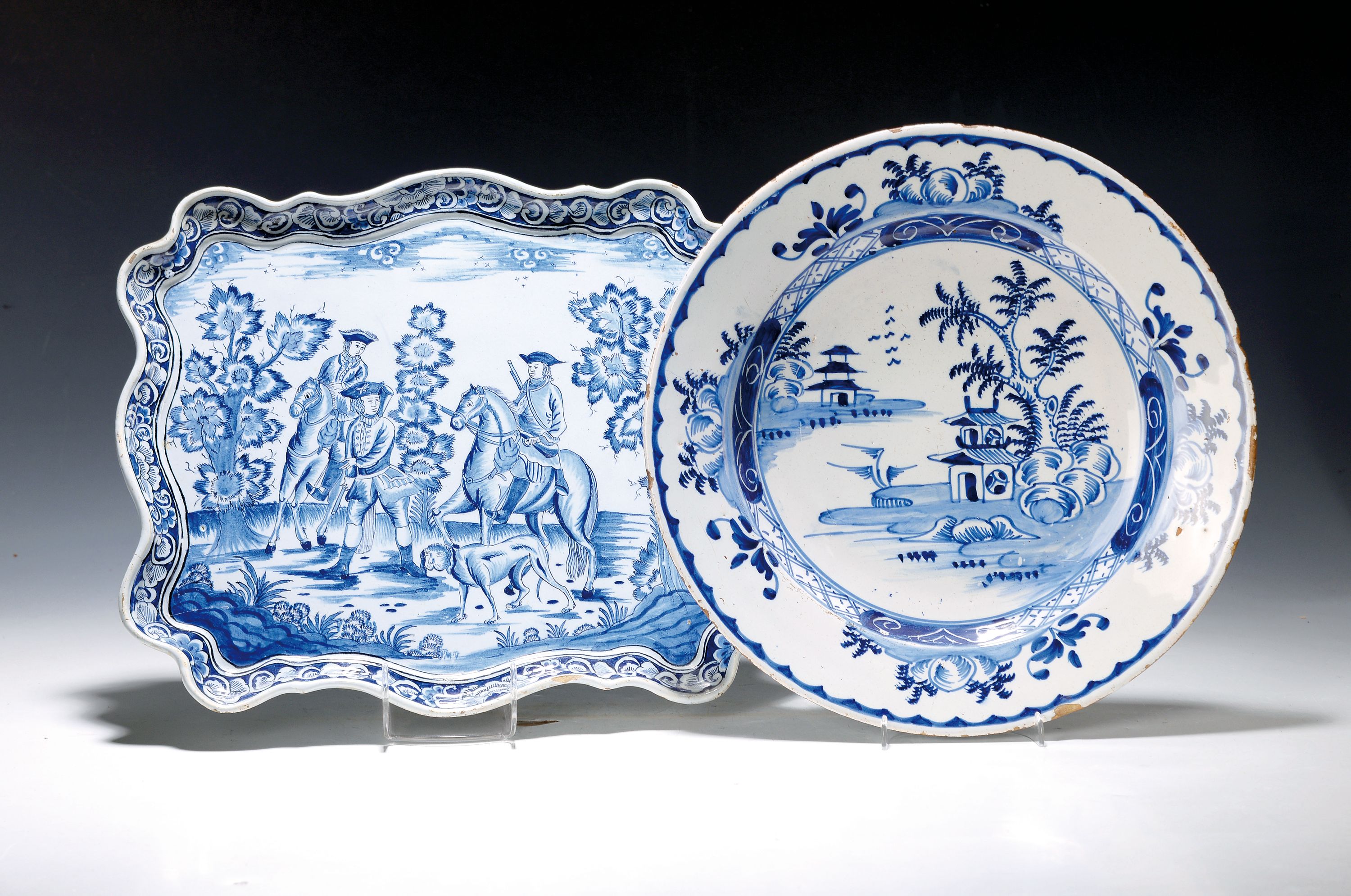 Platte und Teller, Barock, 18. Jh., rechteckige Fayenceplatte mit grober Jagdszene, zwei Reiter und ein Jäger mit Jagdhund in stil. Landschaft, ...