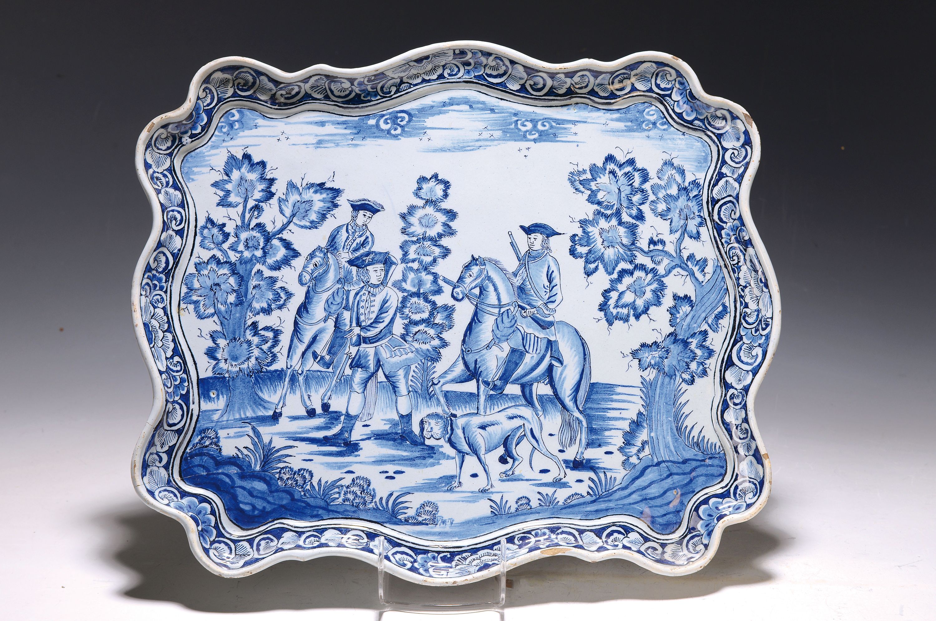 Detail b: Platte und Teller, Barock, 18. Jh., rechteckige Fayenceplatte mit grober Jagdszene, zwei Reiter und ein Jäger mit Jagdhund in stil. Landschaft, ...