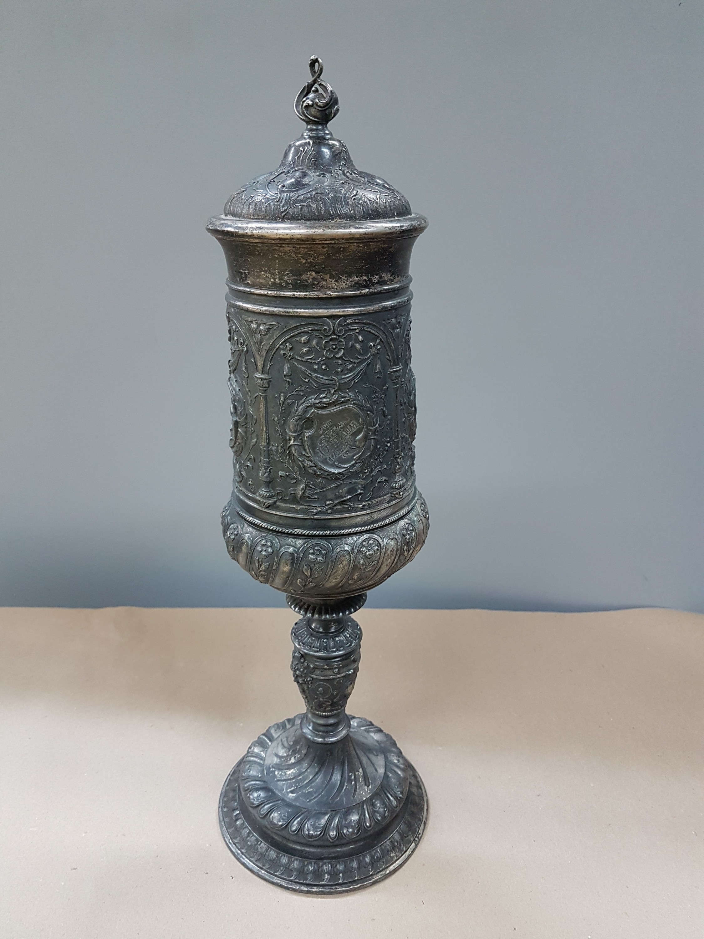 Detail a: Deckelpokal, deutsch, WMF, um 1890, Legierung I/O, reich reliefiert mit Akanthus, Palmetten und Ranken, Inschrift: Viribus Unitis, die Lehrer der ...