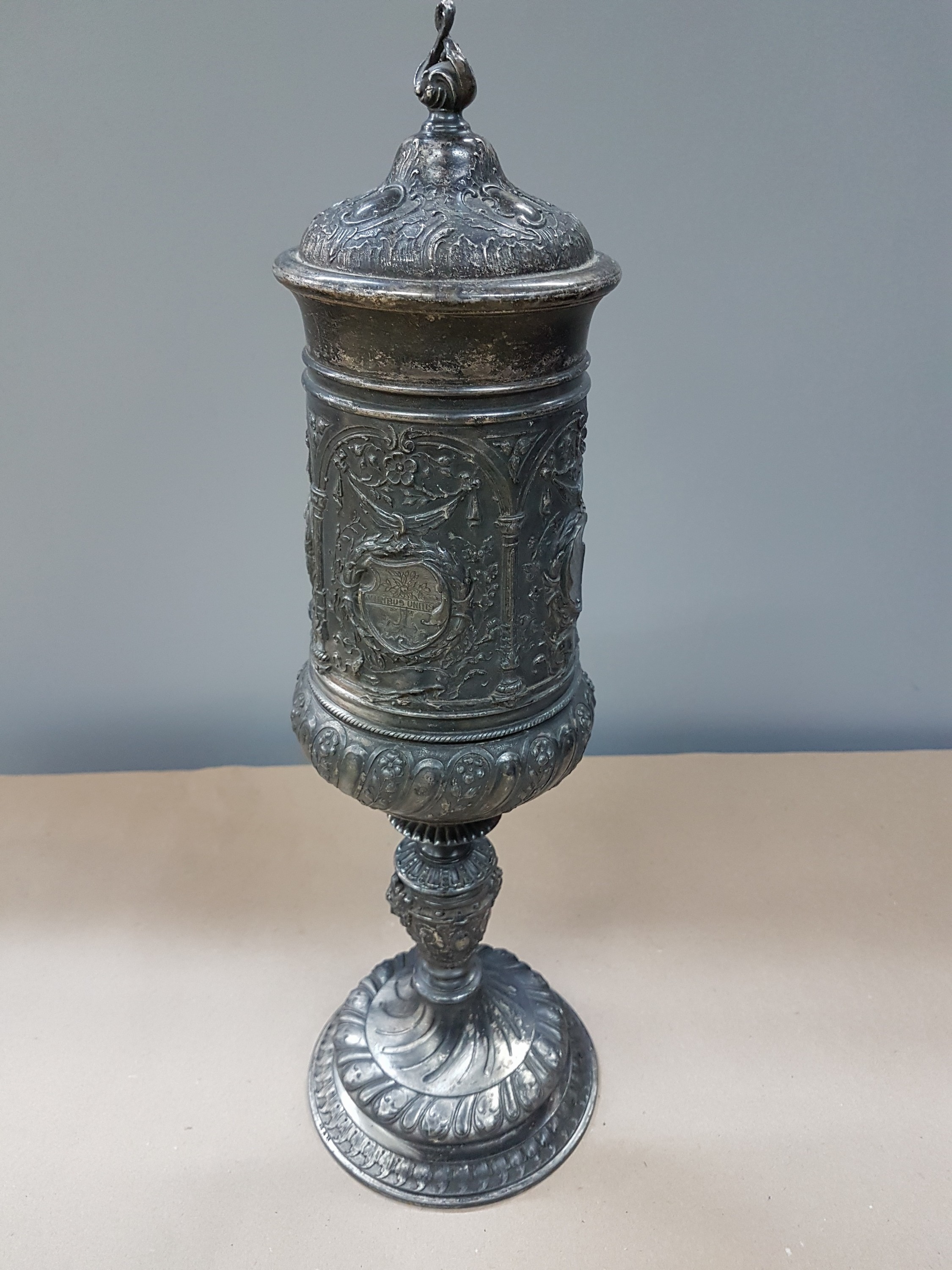 Detail c: Deckelpokal, deutsch, WMF, um 1890, Legierung I/O, reich reliefiert mit Akanthus, Palmetten und Ranken, Inschrift: Viribus Unitis, die Lehrer der ...
