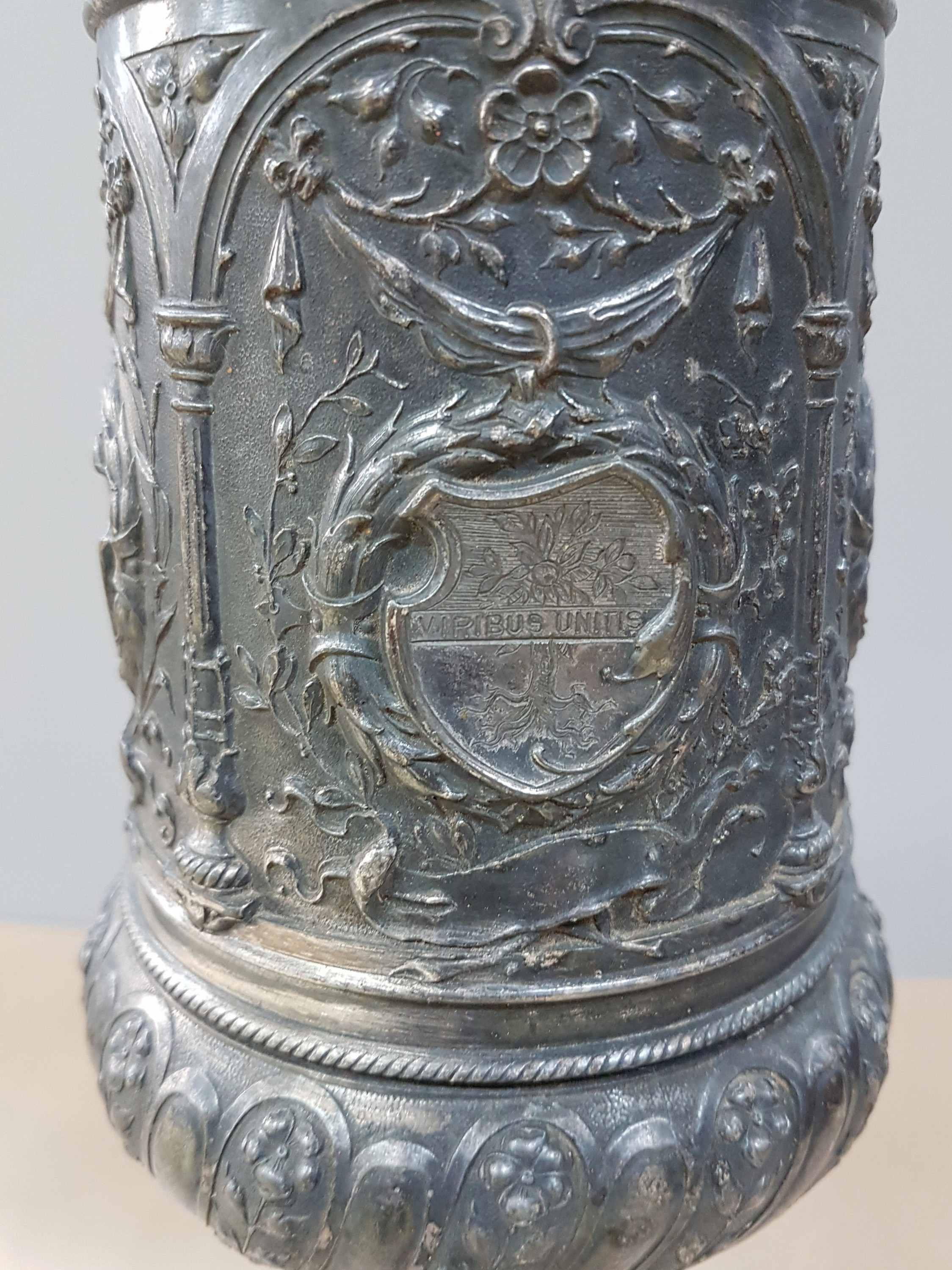 Detail g: Deckelpokal, deutsch, WMF, um 1890, Legierung I/O, reich reliefiert mit Akanthus, Palmetten und Ranken, Inschrift: Viribus Unitis, die Lehrer der ...