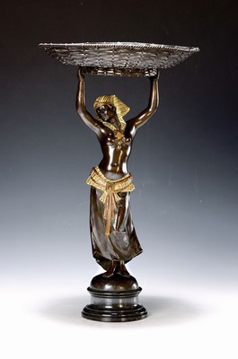 Image 26780672 - Offering bowl or vide poche, France, around 1910, in the form of a fully sculptural Egyptian woman carrying a basket over her head, cast metal with a bronze and gold patina, height approx. 38cm
