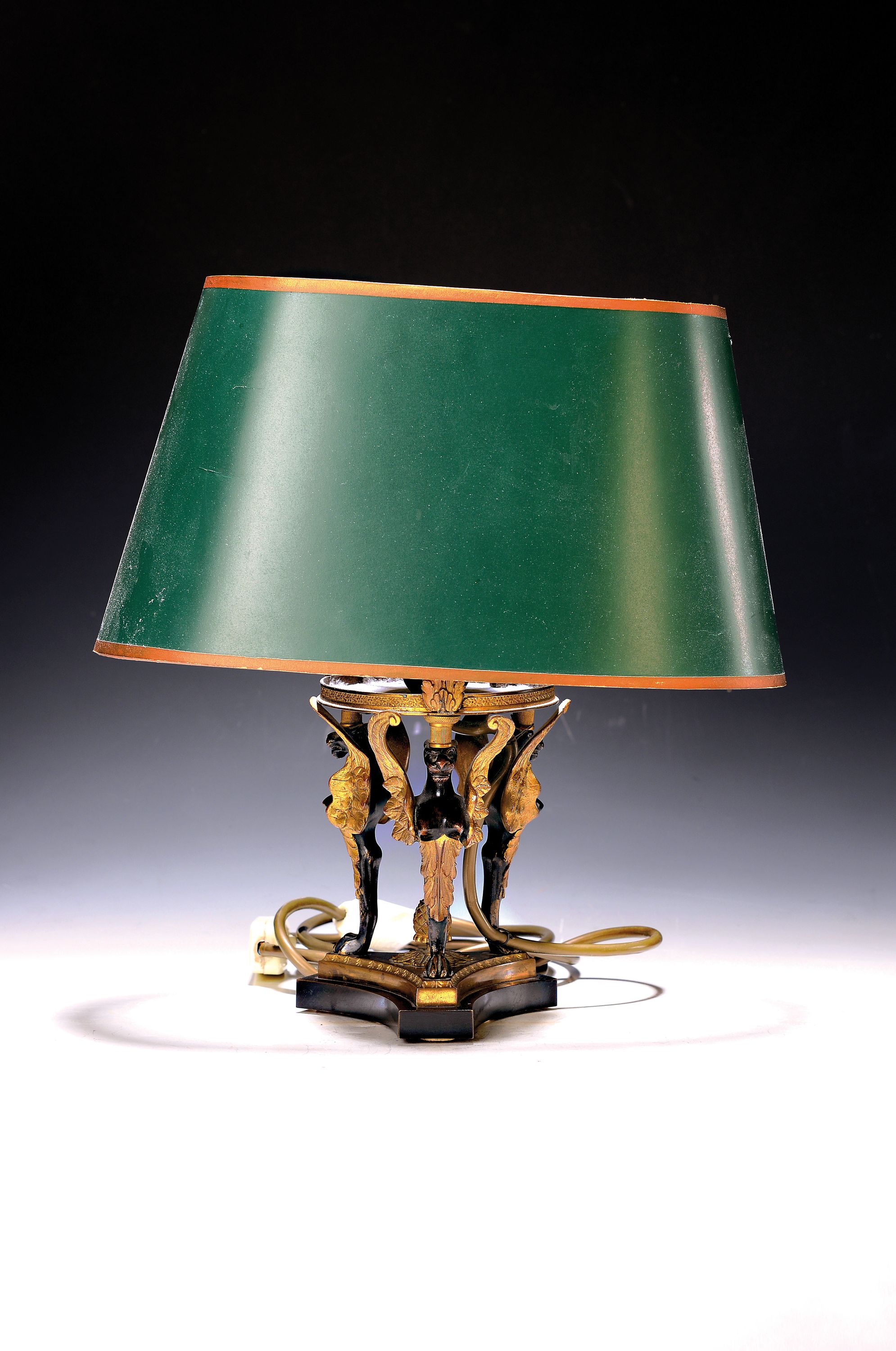 Tischlampe mit Bronzefuß, 20. Jh., drei Chimären, patiniert, umgearbeitet, eine Brennstelle, Schirm l. beschädigt, Elektr. nicht geprüft, H. ca. ...