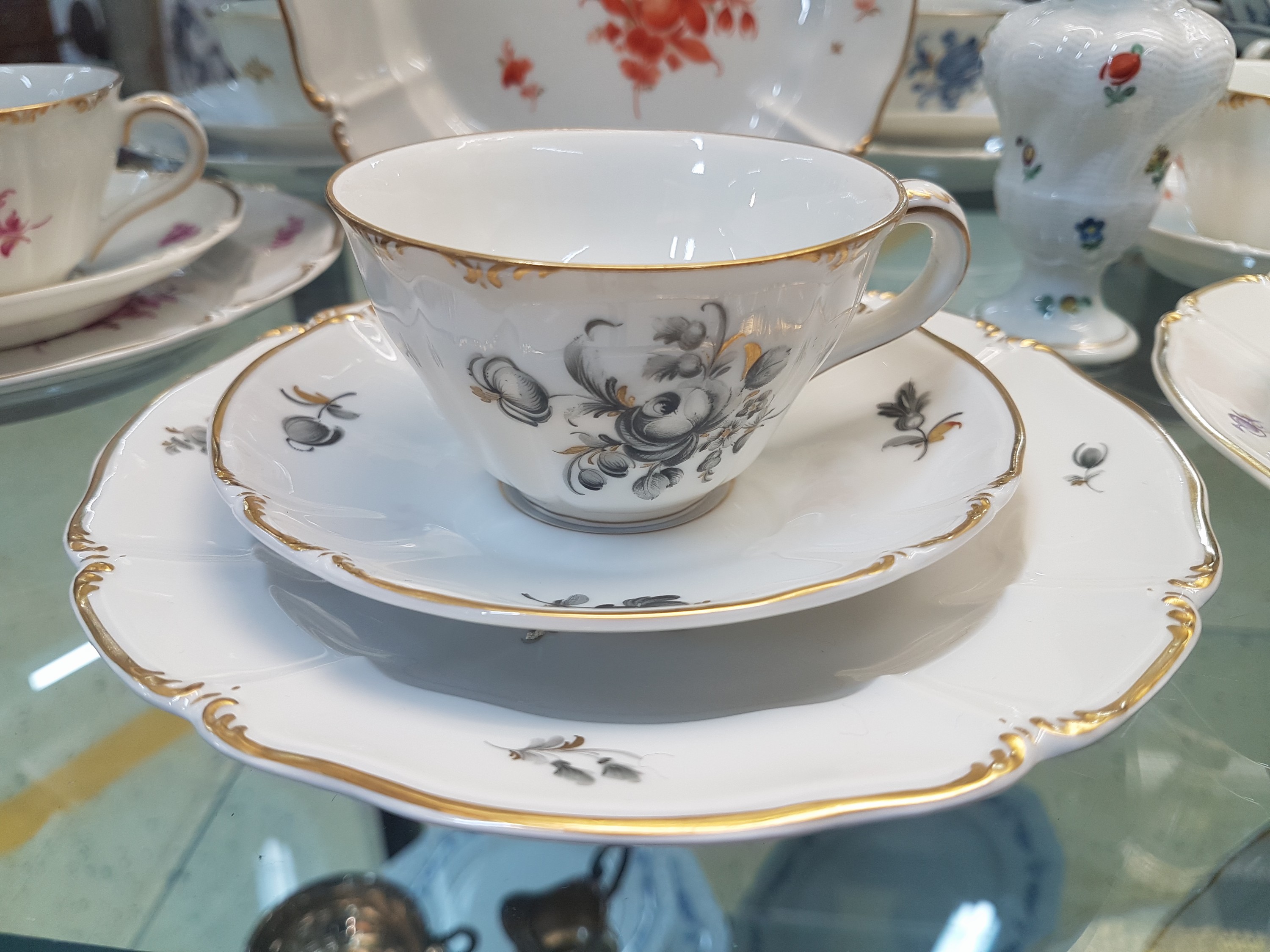 Detail c: 6 Kaffeegedecke und ein Väschen, Nymphenburg, 20. Jh., Blumenmalerei, Goldrand, Teller D. 17.5 cm