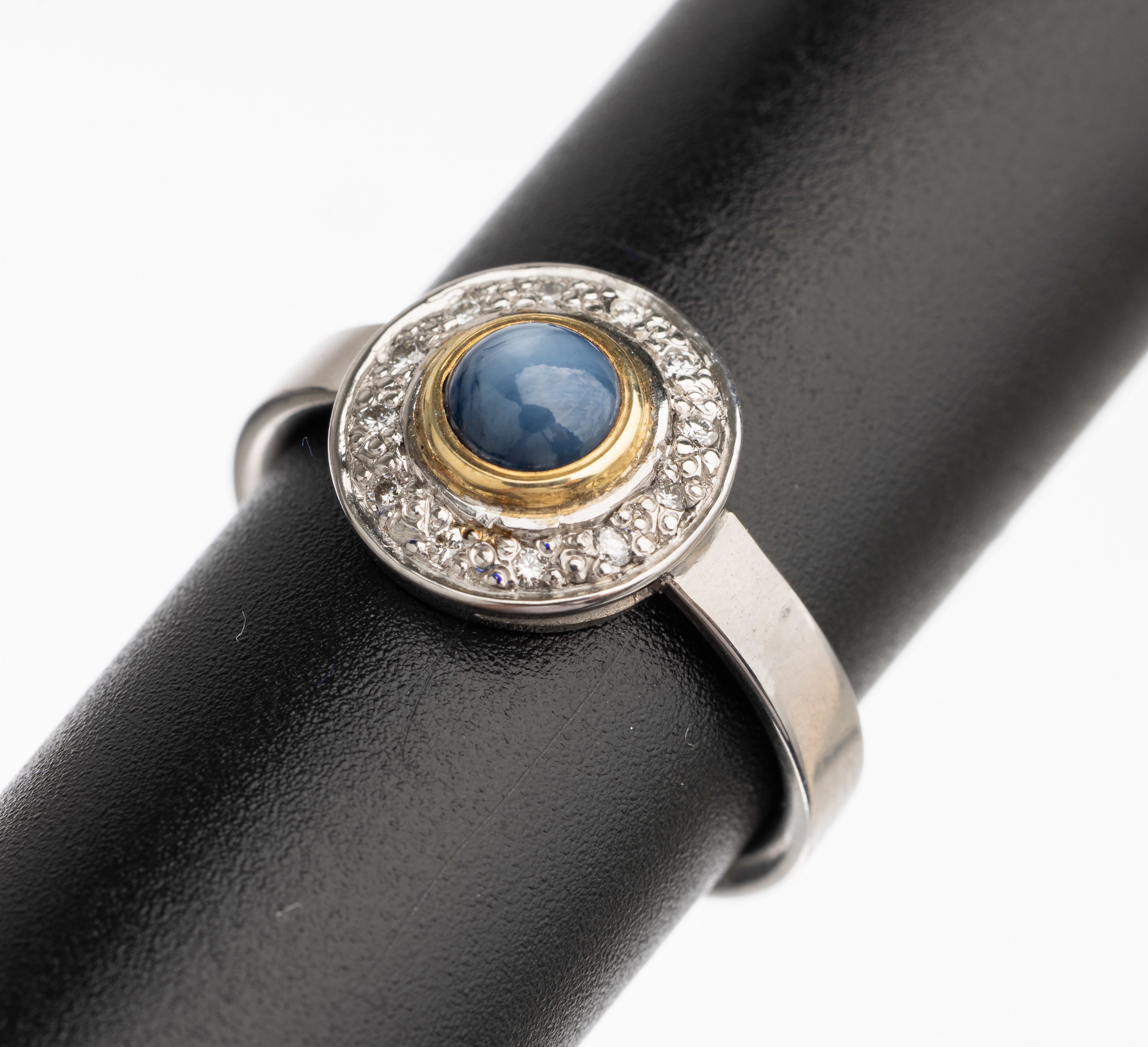 14 kt Gold Saphir Brillant Ring, WG/GG 585/000, in GG gefasster Sternsaphircabochon ca. 0.80 ct, umgeben von 12 Brillanten zus. ca. 0.07 ct ...