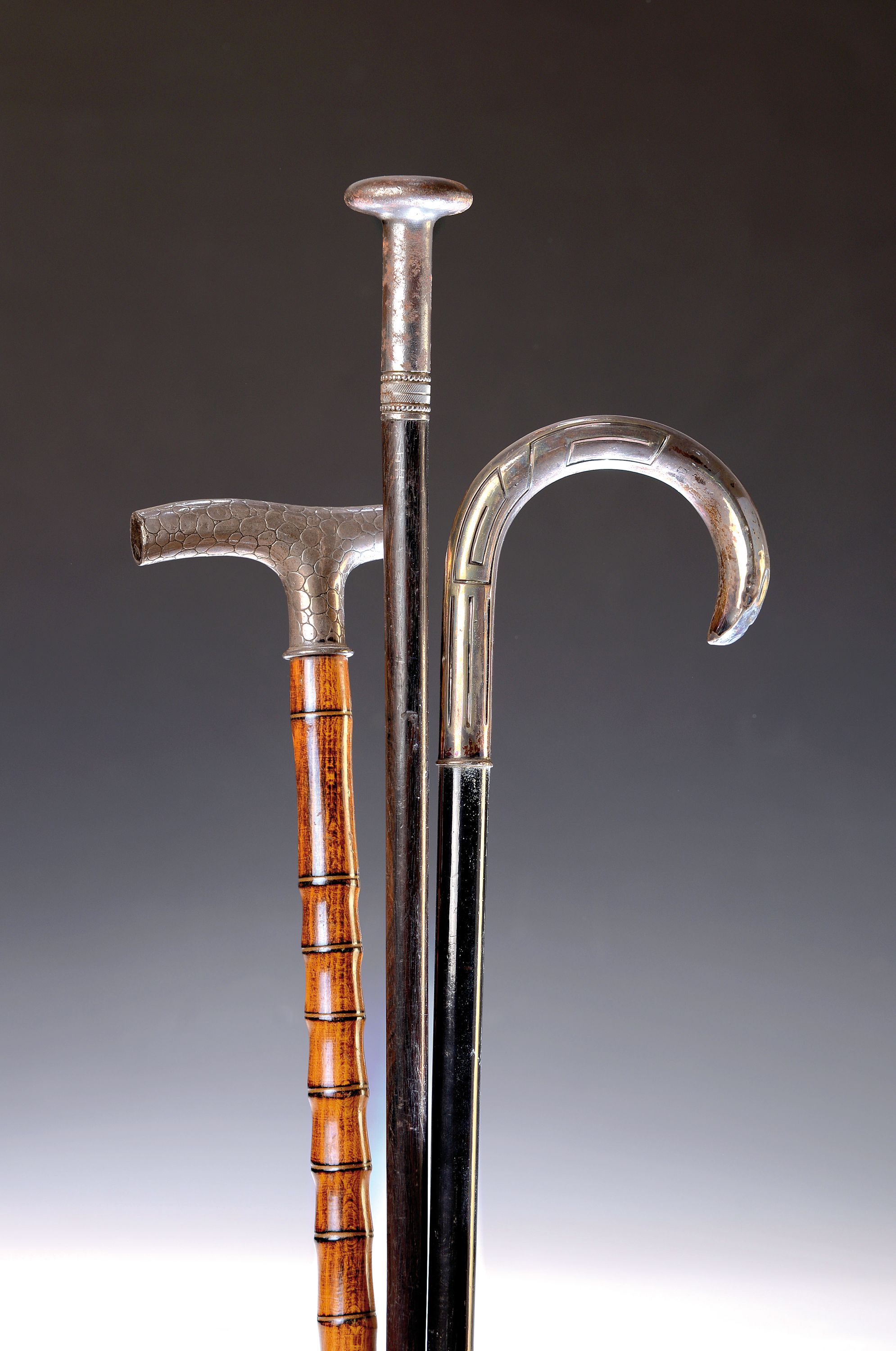 Drei Gehstöcke, deutsch, um 1900, je mit Holzschuß, Rundhaken 800er-Silber mit geometrisierendem Dekor (l. best.) L. 90 cm; Fritz-Griff ...