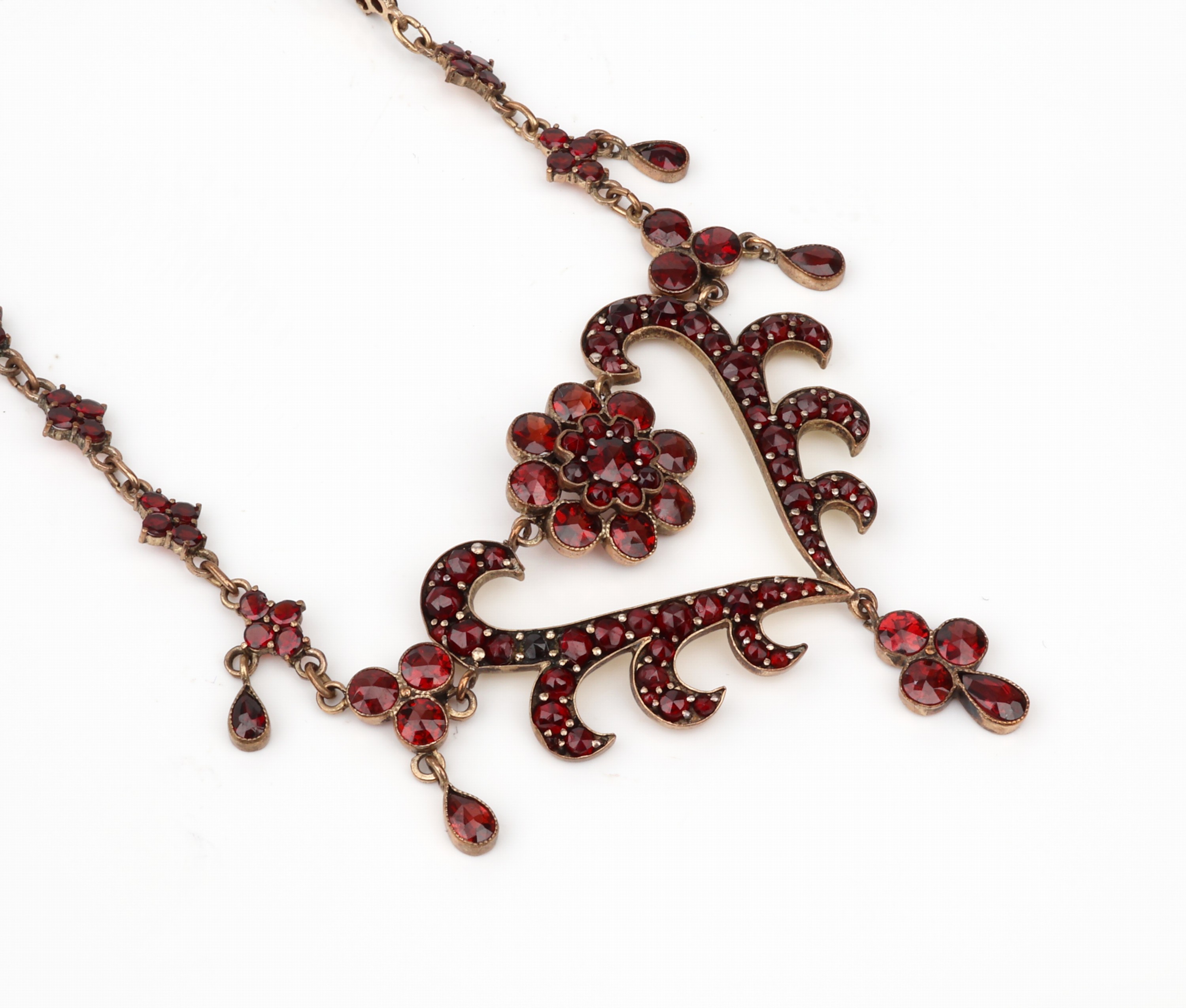 Granat-Collier, Böhmen um 1880/90, Tombak verg., Mittelteil in Herzform. bes. mit rundfacett. Granate, z.T. mit bewegl. Abhängung, L. ca. 47 cm, ...