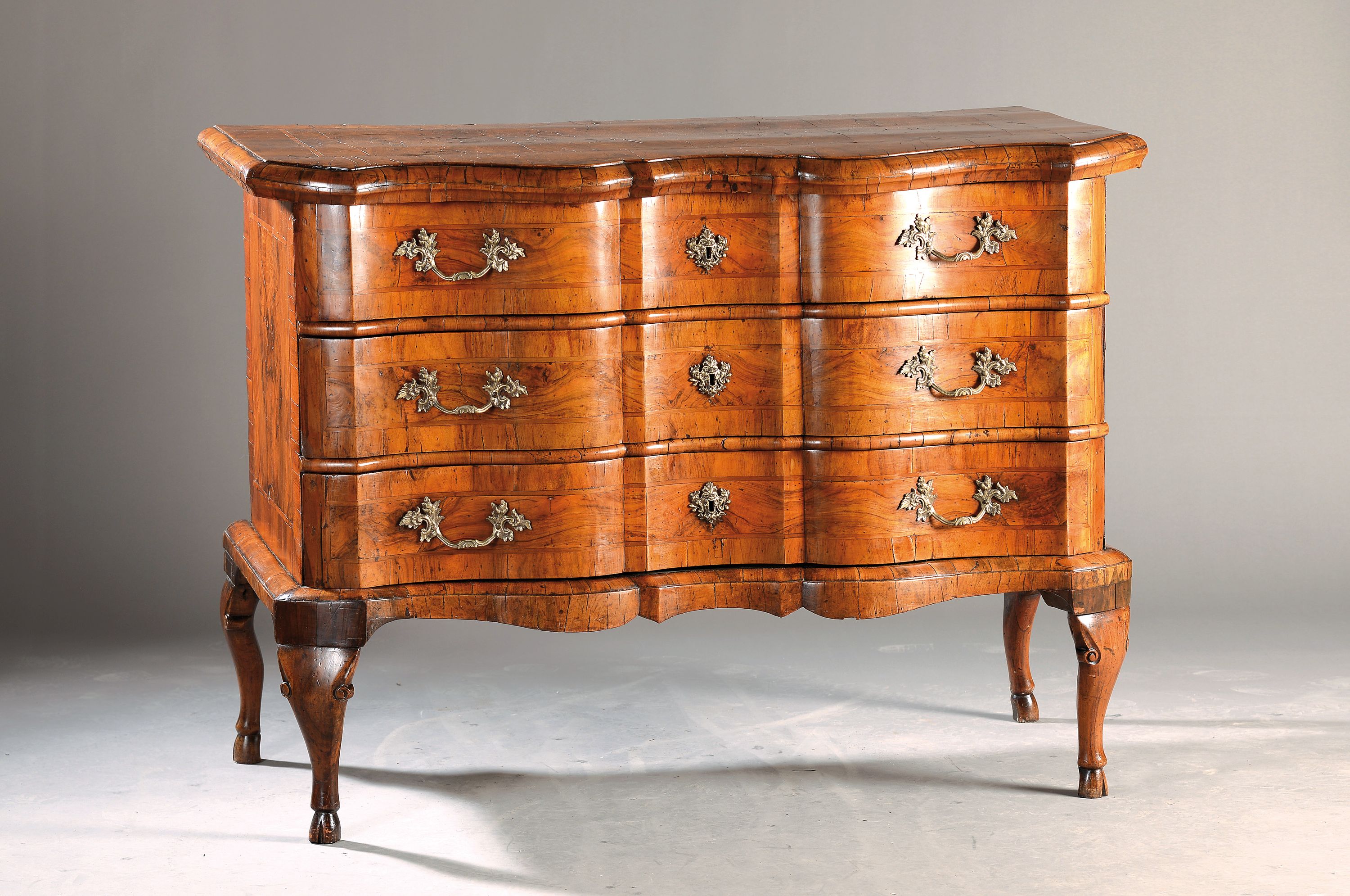 Barock-Kommode, um 1730/40, Nußbaumfurnier, 3 Schubladen mehrfach geschweift, orig. Messingbeschläge, schöne Patina, auf leichten geschwungenen ...