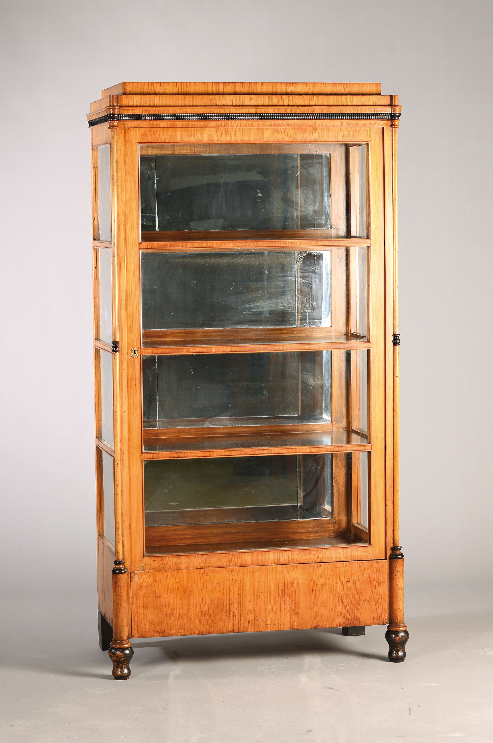 Biedermeier Vitrine, um 1825/30, Kirschbaumfurnier, dreiseitig verglast, orig. gewalztes Glas, mehrfach versprosst, innen Einlegeböden, schwarz ...