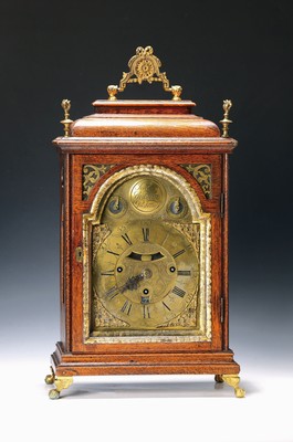 Image 26786443 - Baroque clock with date, quarter-hour strike and musical mechanism (later), Jacob Guldan, Presburg around 1780, wooden case glazed on all sides, carrying handle, 2 flamed corner vases (formerly four), door key and at inner strip are missing, brass arched dial, date window (switches on), in arcus name cartouche (see ref.: Abeler, p. 199), 2 auxiliary dials for firing stop and repeater (to be adjusted), massive Brass plate movement, verge movement with fixed and front swing pendulum, transport lock of the pendulum is missing, 3 fixed barrels, positions are missing, strike on the small bell every quarter of at hour, subsequent strike on the large bell at the full hour, then the musical mechanism is triggered with 3 melodies, approx. 85 Tongues, switch-off to be adjusted, height with handle approx. 53cm, key missing, condition of movement 3, housing 2-3