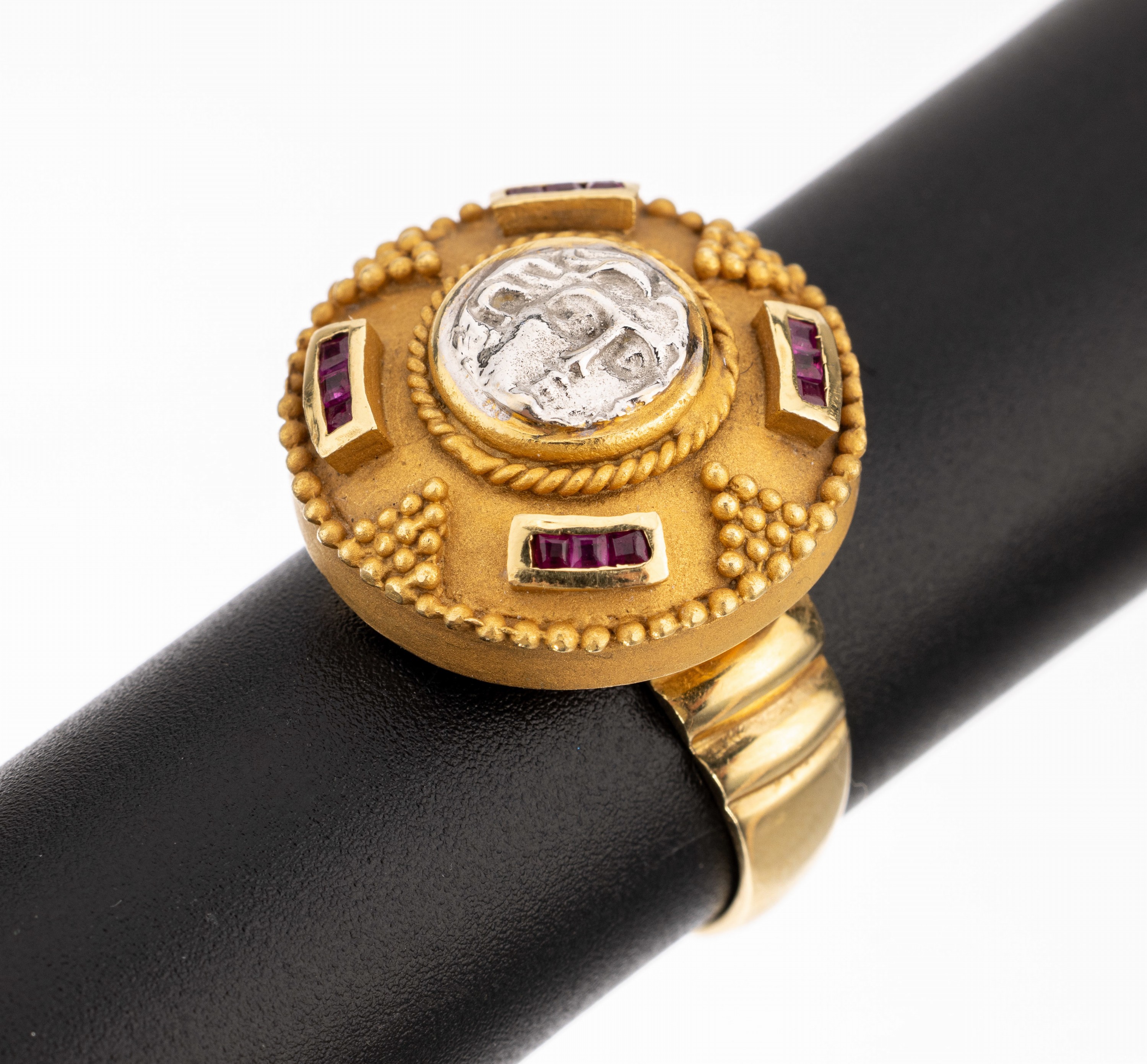 18 kt Gold Rubin-Ring, GG 750/000, mittig aufgelegter stilis. Medusenkopf, aufwändige Goldschmiedearbeit mit Kordelver- zierung und Granulaten, 12 ...