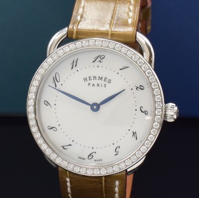 26787177a - HERMES wristwatch series Arceau reference AR5.530, stainless steel case including original leather strap with original buckle, bezel lavish with diamonds, quartz, case back 5-times screwed down, mother of pearl dial with Arabic hour, blued steel hands, display of hour & minutes, diameter approx. 36 mm, Hermes storage back enclosed, unworn stock, condition 1-2