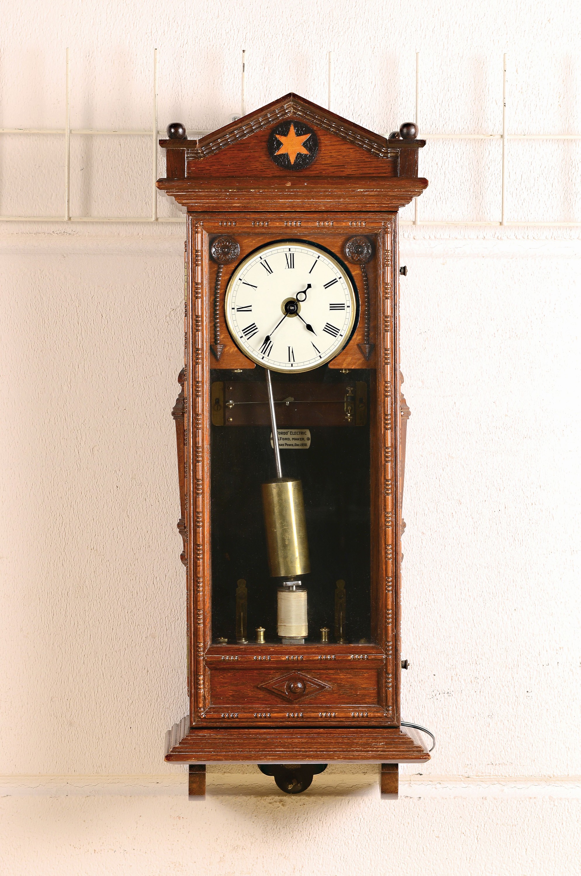 Wanduhr, elektrisch, um 1930, Holzgehäuse verziert u. profiliert, sek. lackiert, Giebelabschluss, Türverschluss rechts mittels einzelner ...
