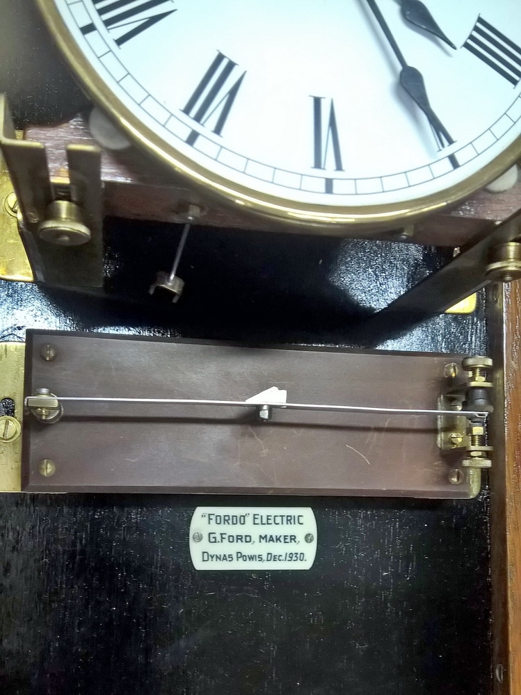 Detail c: Wanduhr, elektrisch, um 1930, Holzgehäuse verziert u. profiliert, sek. lackiert, Giebelabschluss, Türverschluss rechts mittels einzelner ...
