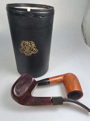 26790376c - Pipe shelf and 22 branded pipes, branded pipes inter alia 5 x Dunhill, Nording, Briar, Bang, 3 x Savinelli, Killarmey, Vauens, Dansk and Peterson, inter alia, in addition one Meerschaum pipe, all used, partly with traces of usage, corner shelf in oak with floral carving, in addition slightly accessories, 84 x 35 cm, Thigh depth 25 cm in addition tobacco vessel, two pipes without mouthpiecee