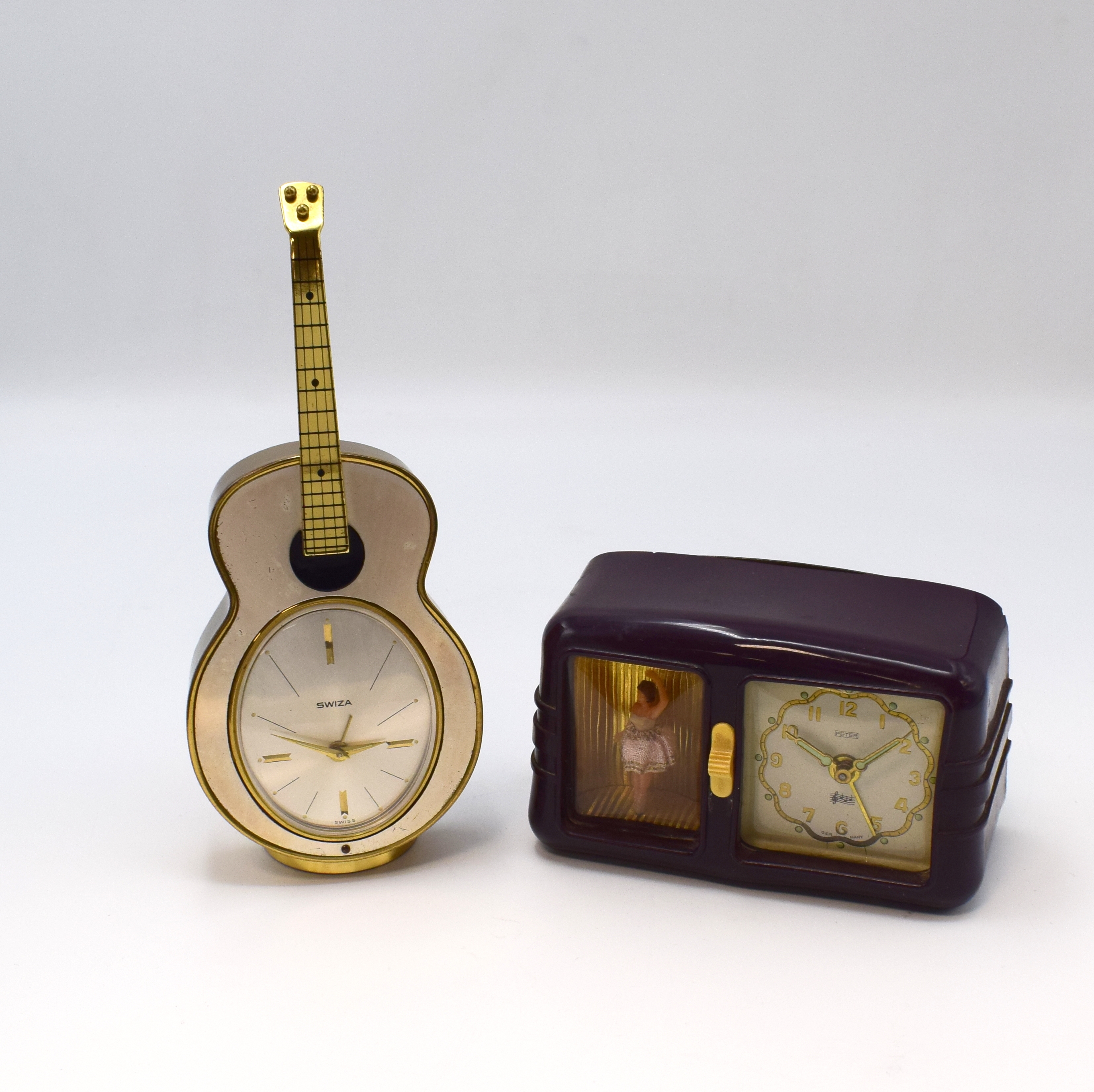SWIZA / PETER Konvolut von 2 Musik-Weckern, Schweiz / Deutschland um 1950, 1) SWIZA, lack. Messinggeh. in Gitarren-Form, silb. ovales Zifferbl., H. ...