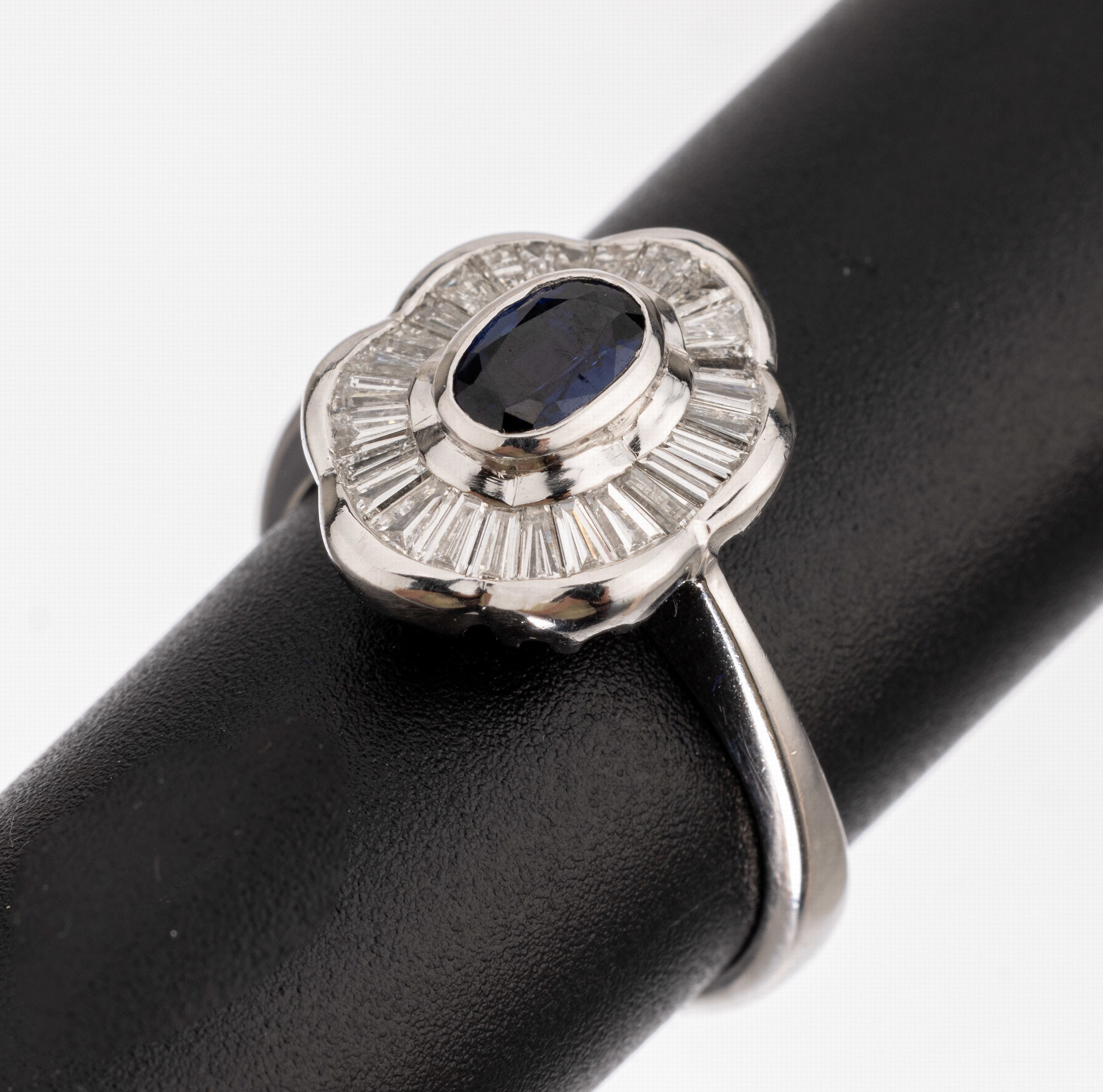 18 kt Gold Diamant Saphir Ring, WG 750/000,ovaler Ringkopf, mittig mit einem ovalfacett. Saphir ca. 0.52 ct, umgeben von Diamant- baguettes zus. ca. ...