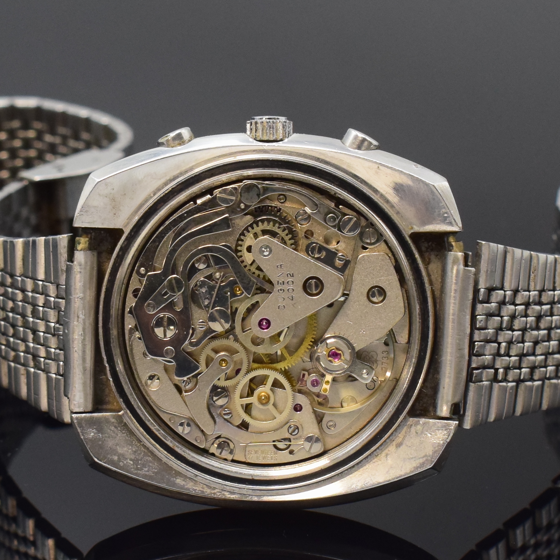 Detail d: DUGENA Armbandchronograph mit Kaliber Valjoux 7733 in Stahl, Schweiz um 1975, Handaufzug, Boden verschr., neutr. Band, silb. Zifferbl. m. aufges. ...