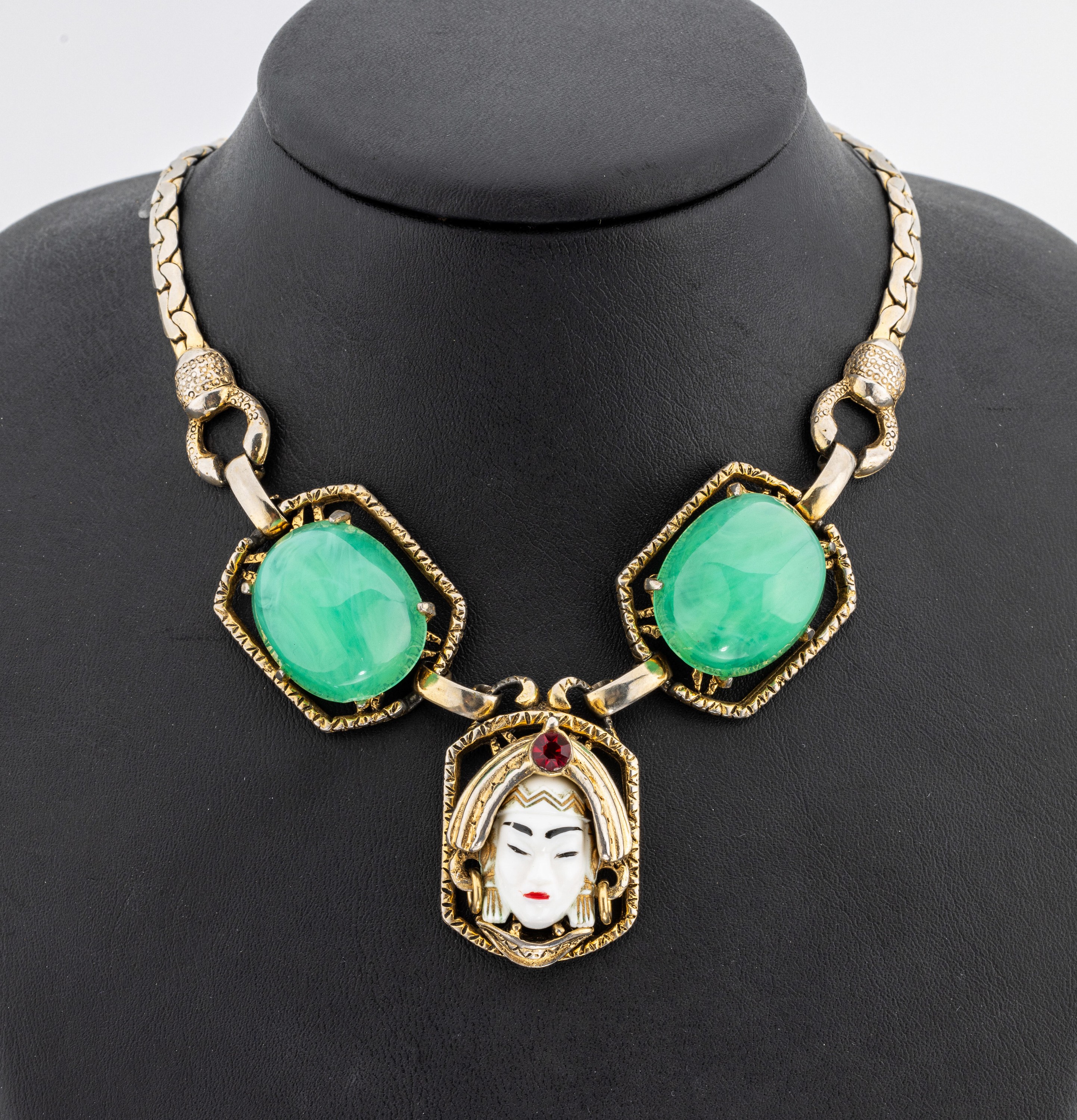 Collier, USA um 1950, Metall verg., Mittelteil mit emaillierten Damenkopf, 2 gr. Chrysoprascabochons, L. variabel ca. 37 - 46 cm, Hakenschließe, ...