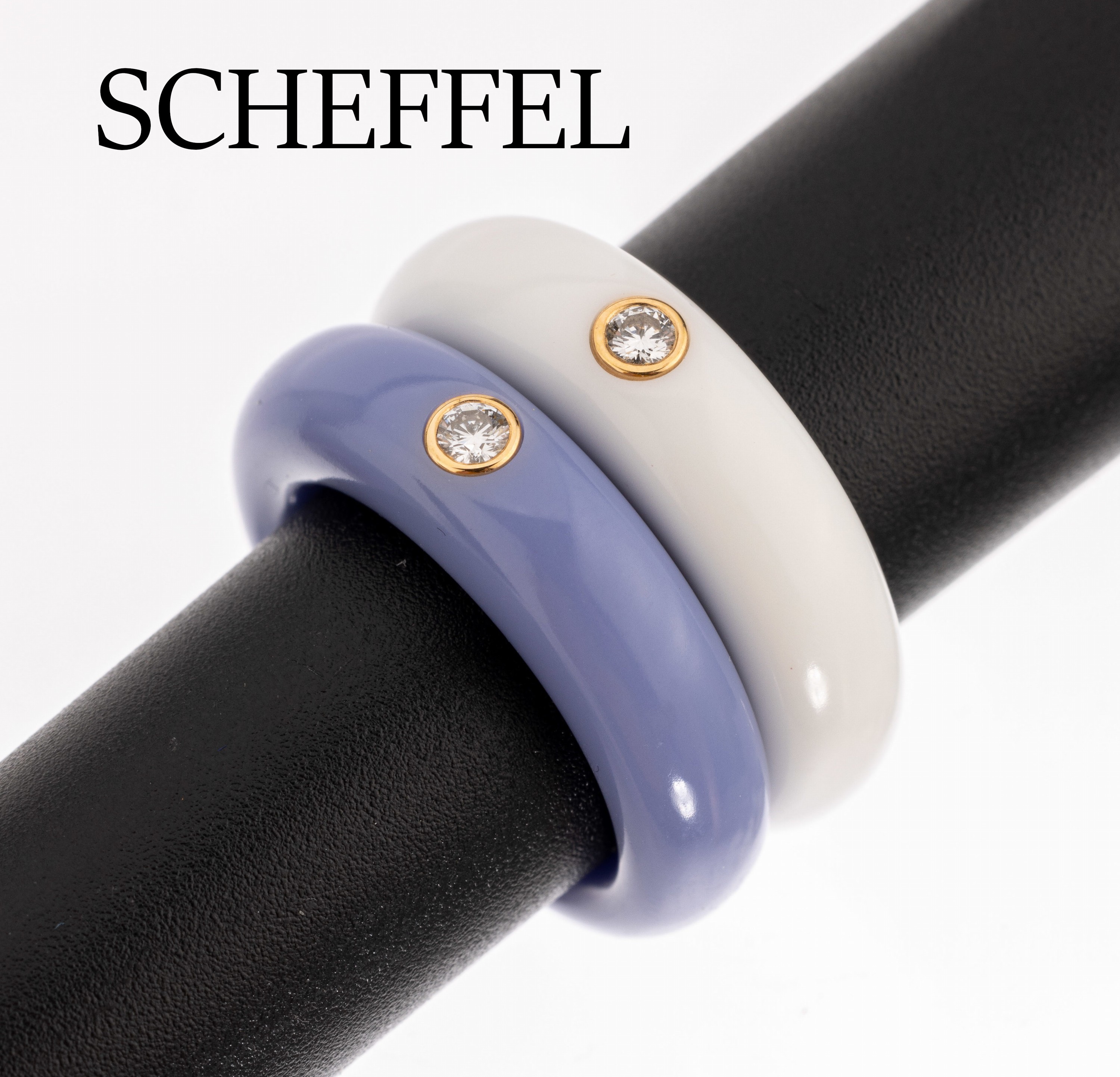 Set 2 SCHEFFEL Brillant-Ringe, 1 x Ringschiene aus weissem Corian, 1 x aus fliederfarb. Corian, jeweils 1 in GG 750/000 gefasster Brillant, zus. ca. ...